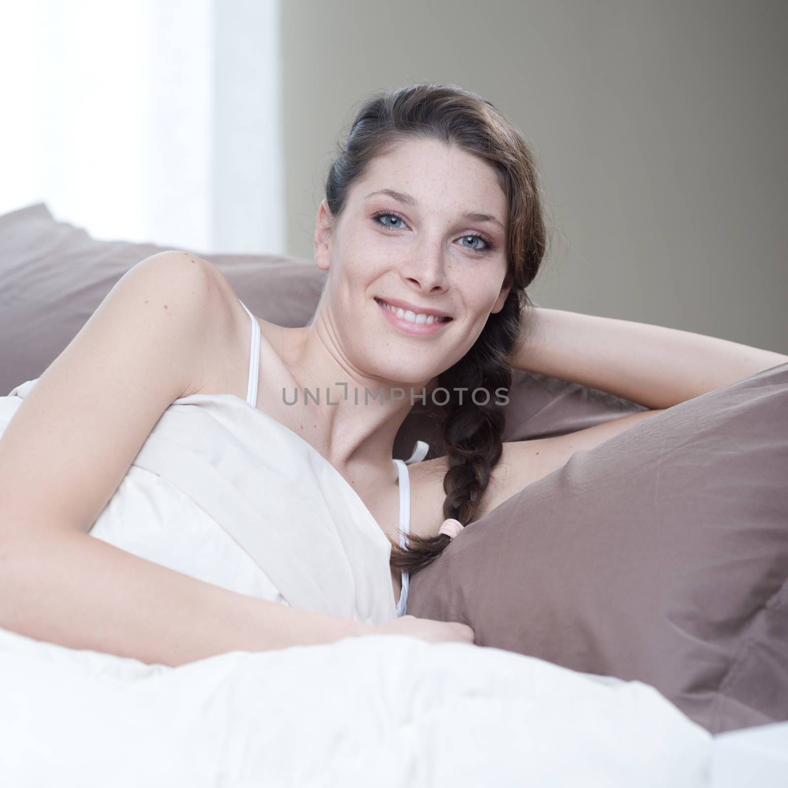 Young woman smiling while lying in bed 