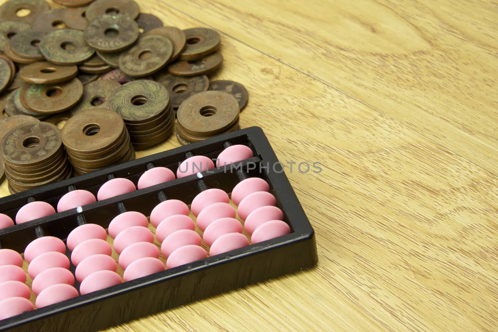 Pile of old ancient coins of Thailand and abacus place with wood background.