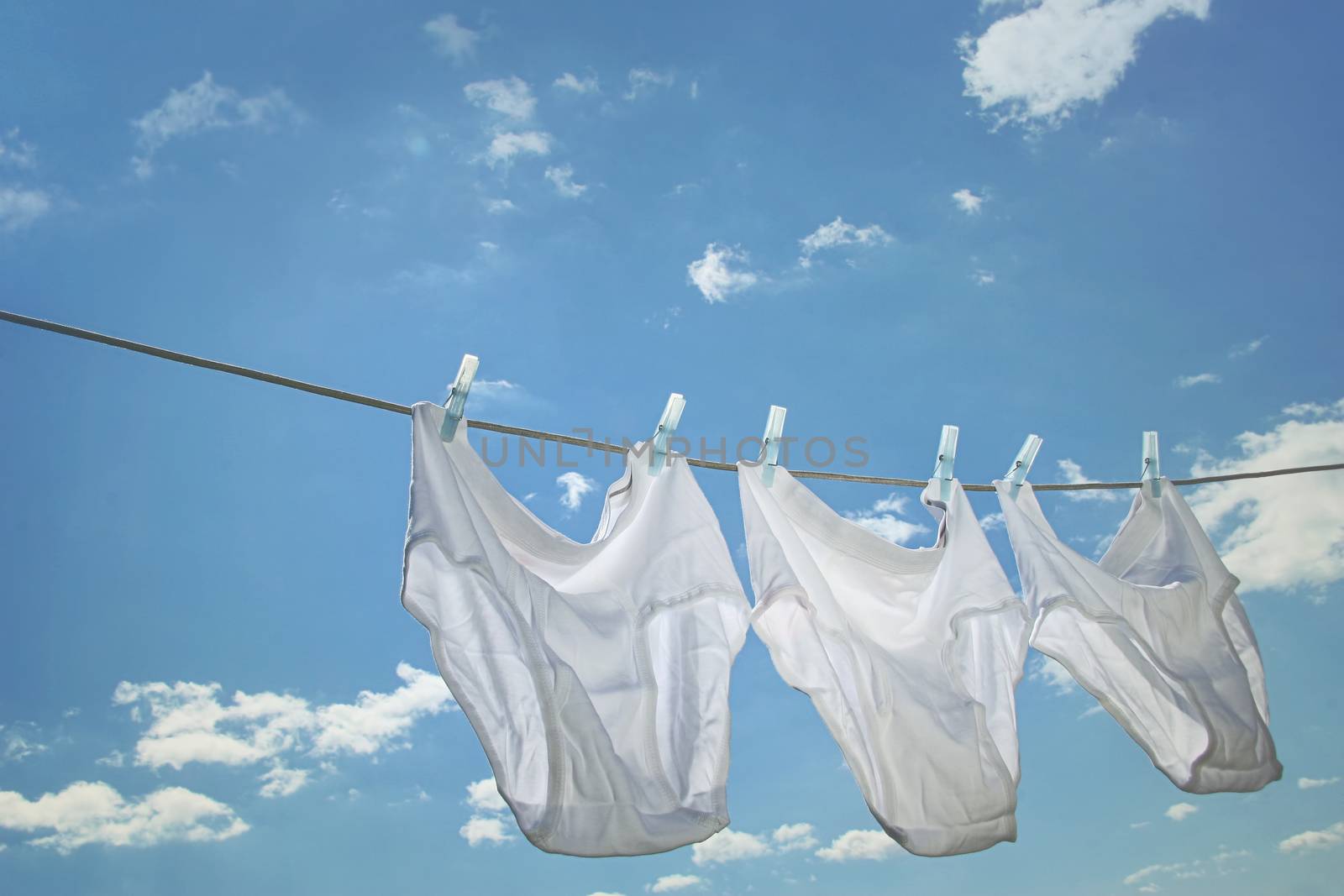Men's underwear hanging on clothesline against blue sky