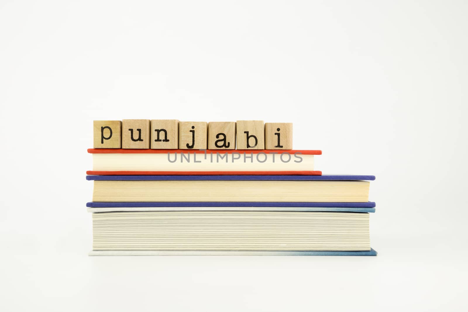 punjabi word on wood stamps stack on books, foreign language and translation concept