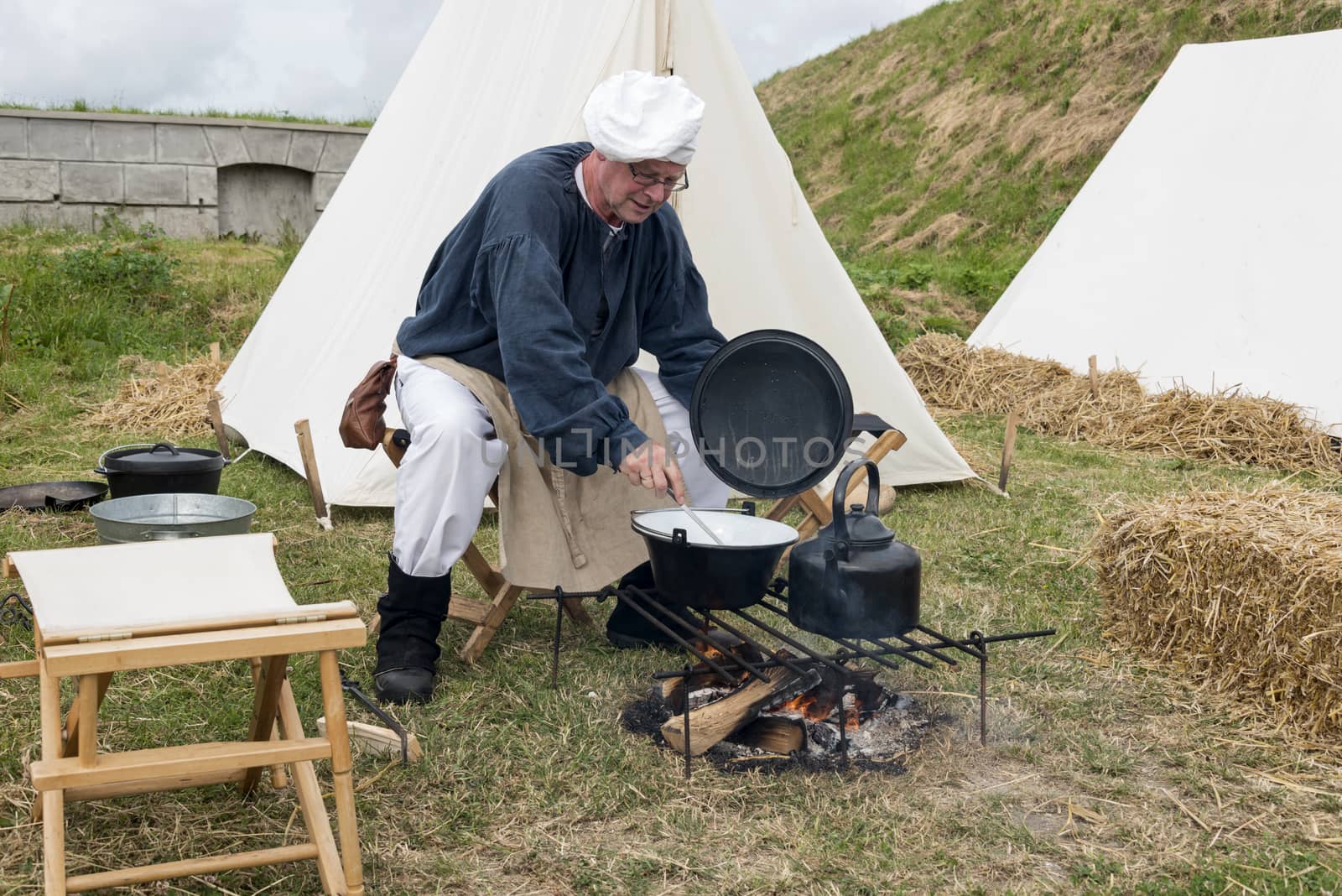 HELLEVOETSLUIS,NETHERLANDS - JUN 28: Man in traditional costume cooking on campfire during the event of the conquest of Hellevoetsluis in 1813