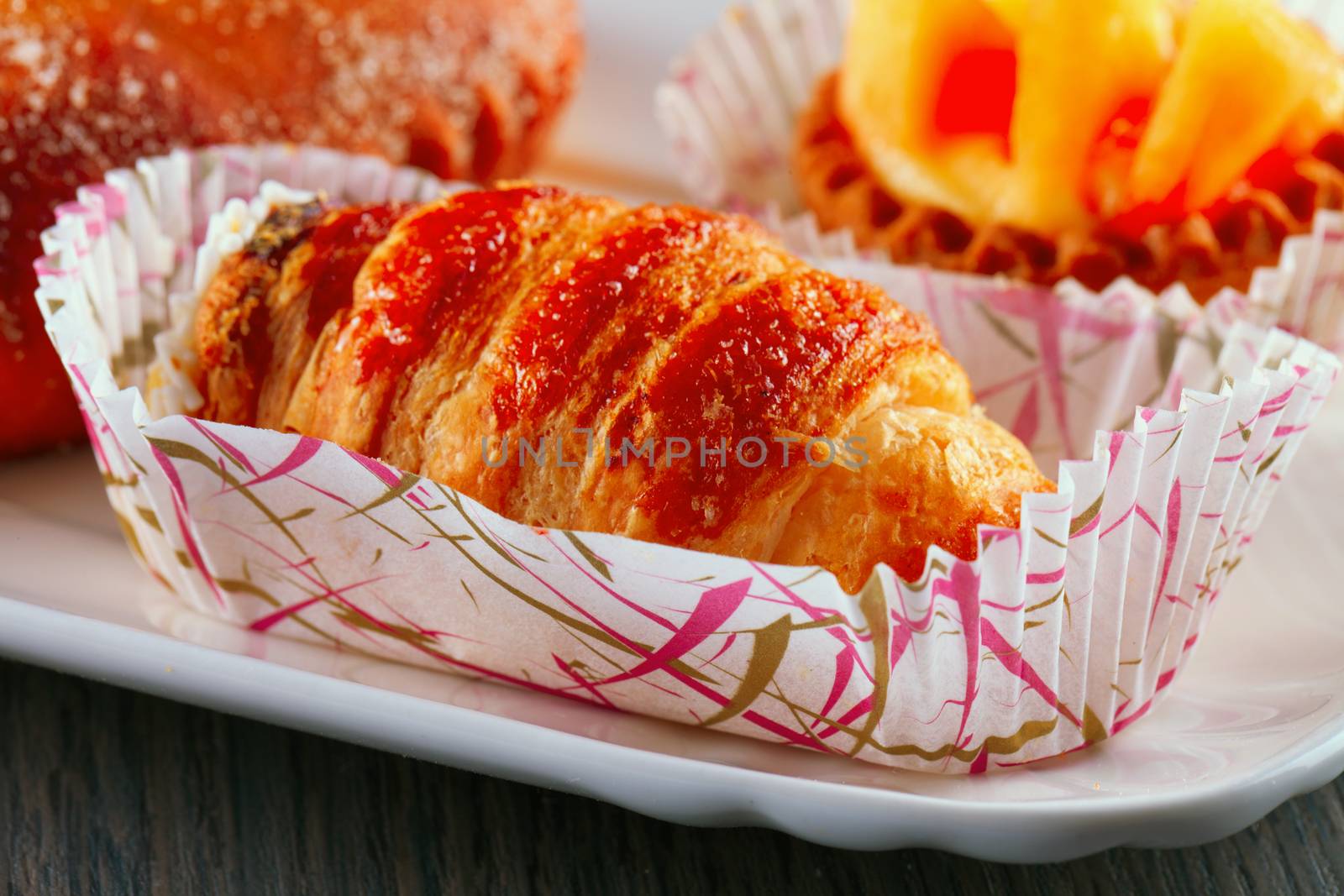 Cannolo pastry over a white ceramic plate, over wooden table