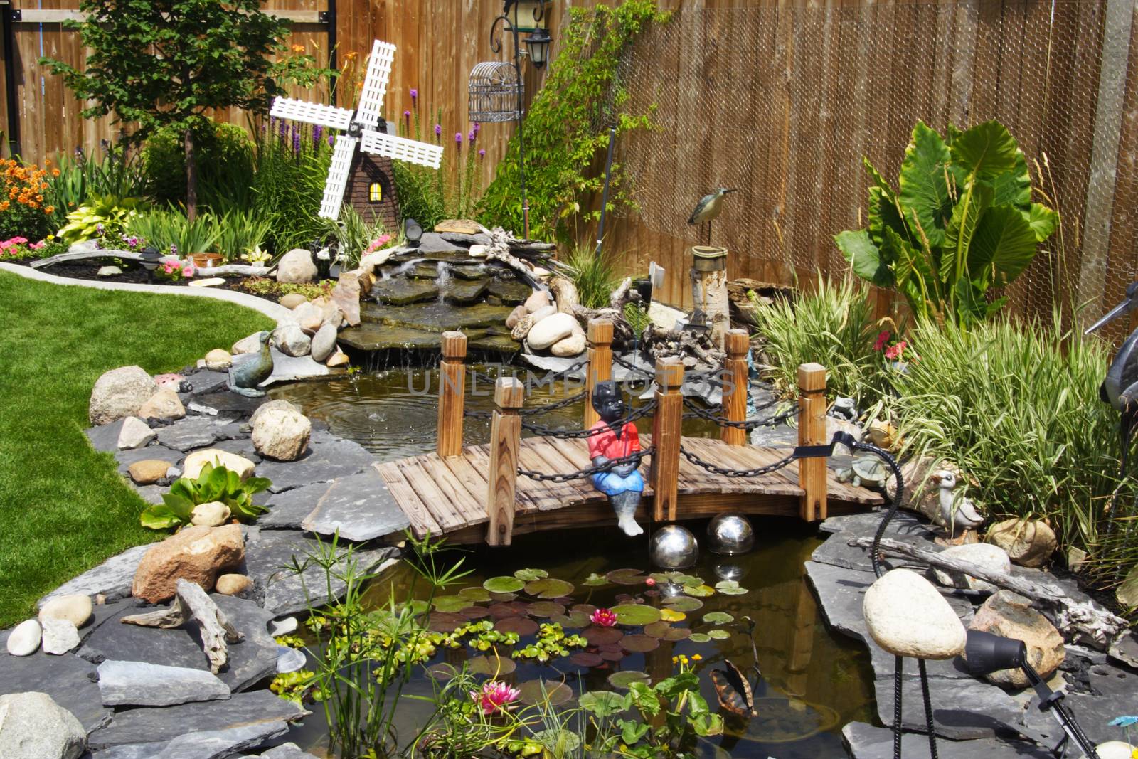 A beautifully designed water garden feature tied into a lovely perennial border makes this backyard a wonderful place to relax and entertain in the summer.