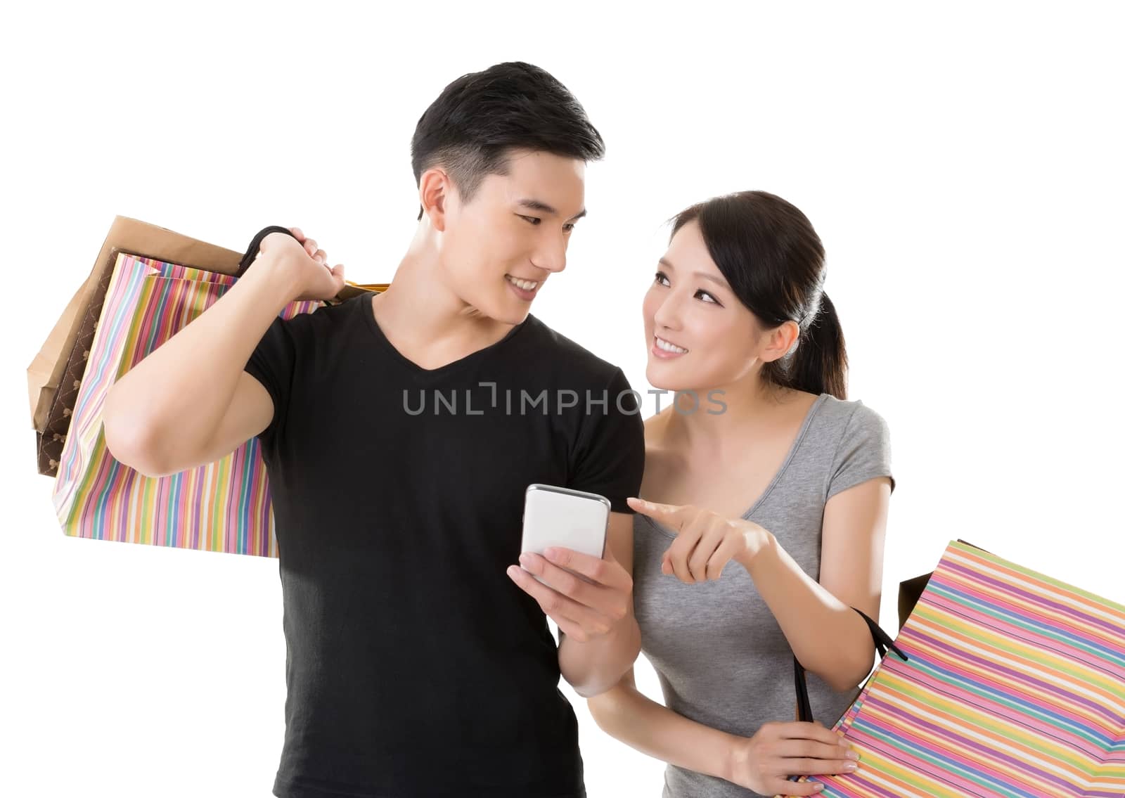 Attractive young Asian couple shopping and looking at cellphone, full length portrait isolated on white background.