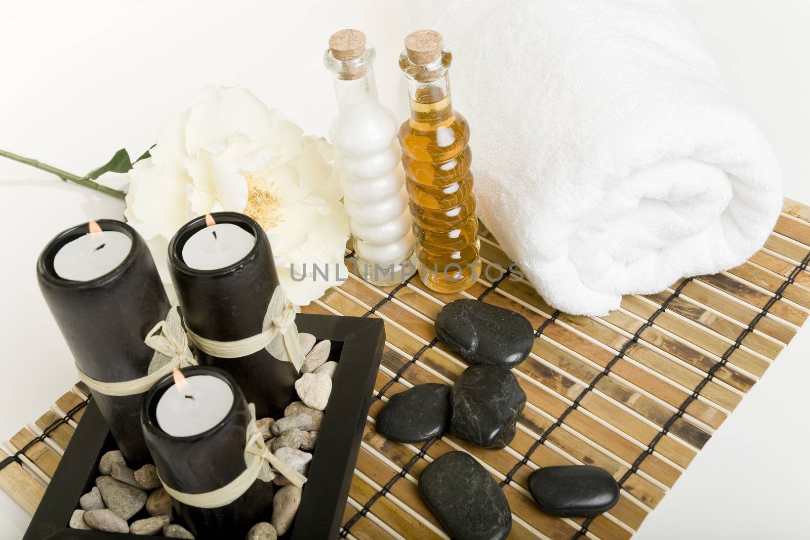 The candles are lit & massage stones, oils, & a towel are all laid out in preparation for a spa treatment.