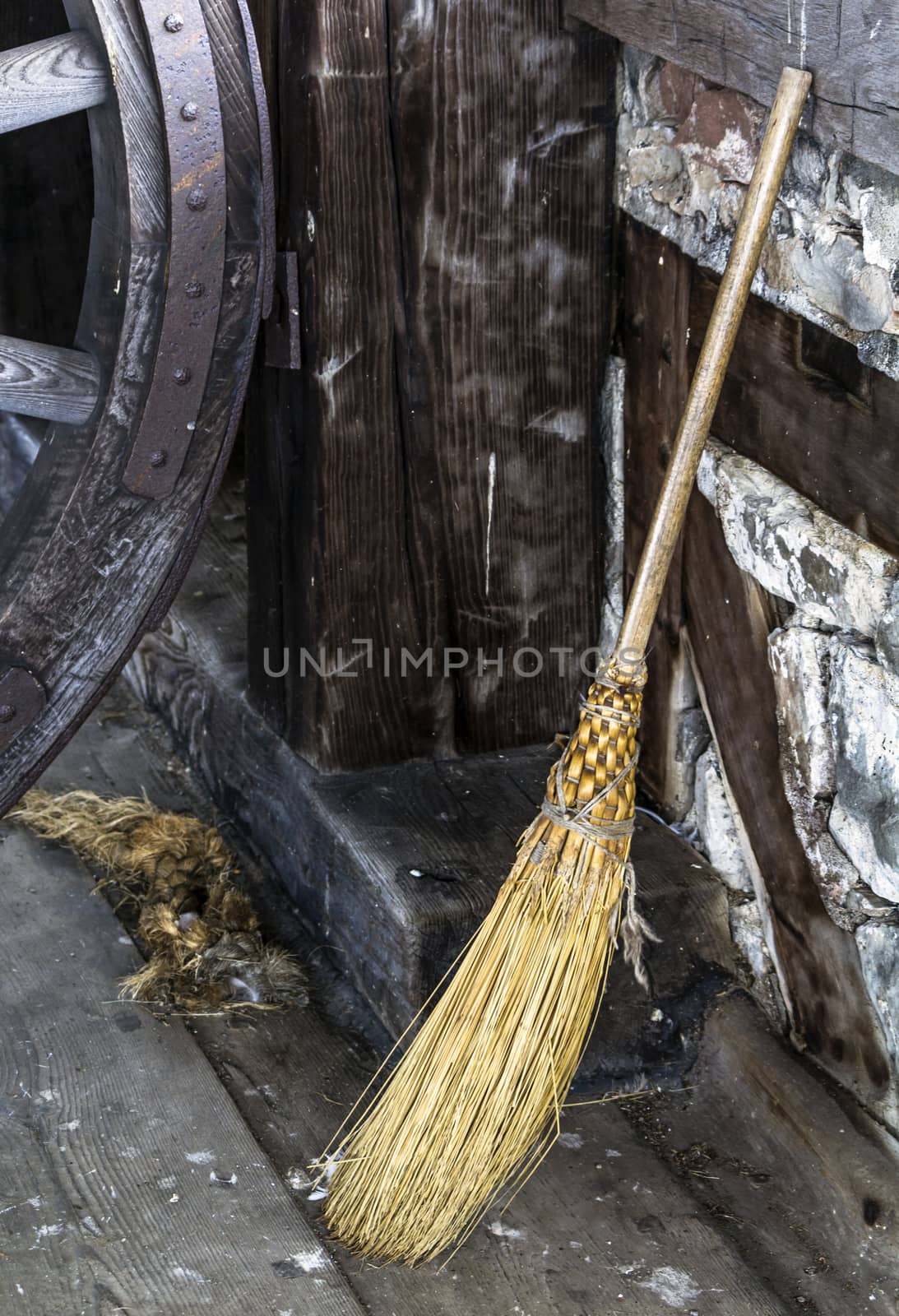 Old fashioned hand crafted straw broom propped up against wall. 