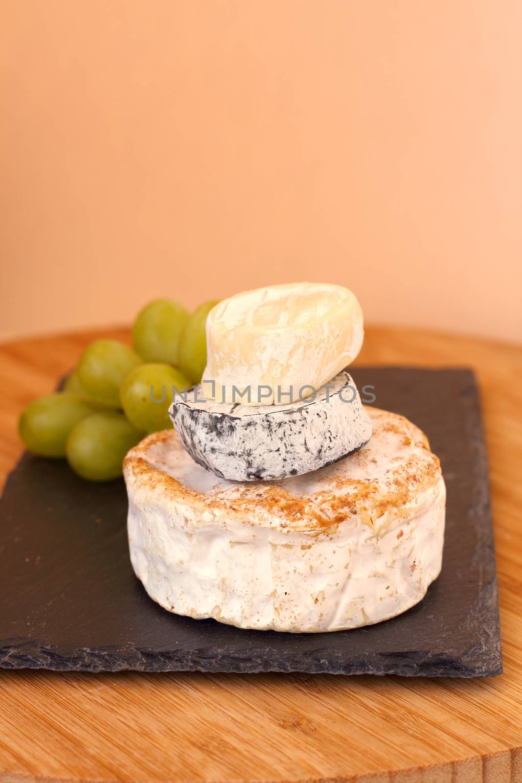 Stack of camembert cheese and grapes on wooden board