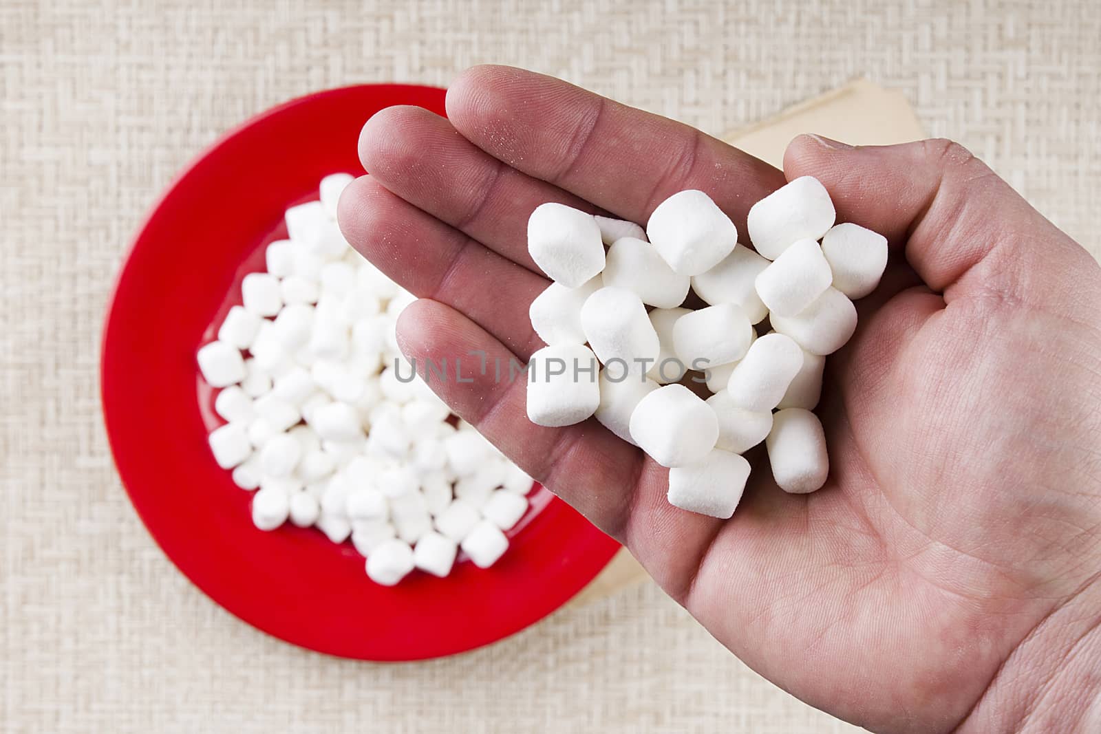 Miniature Marshmallows in a male hand. A food ingredient.