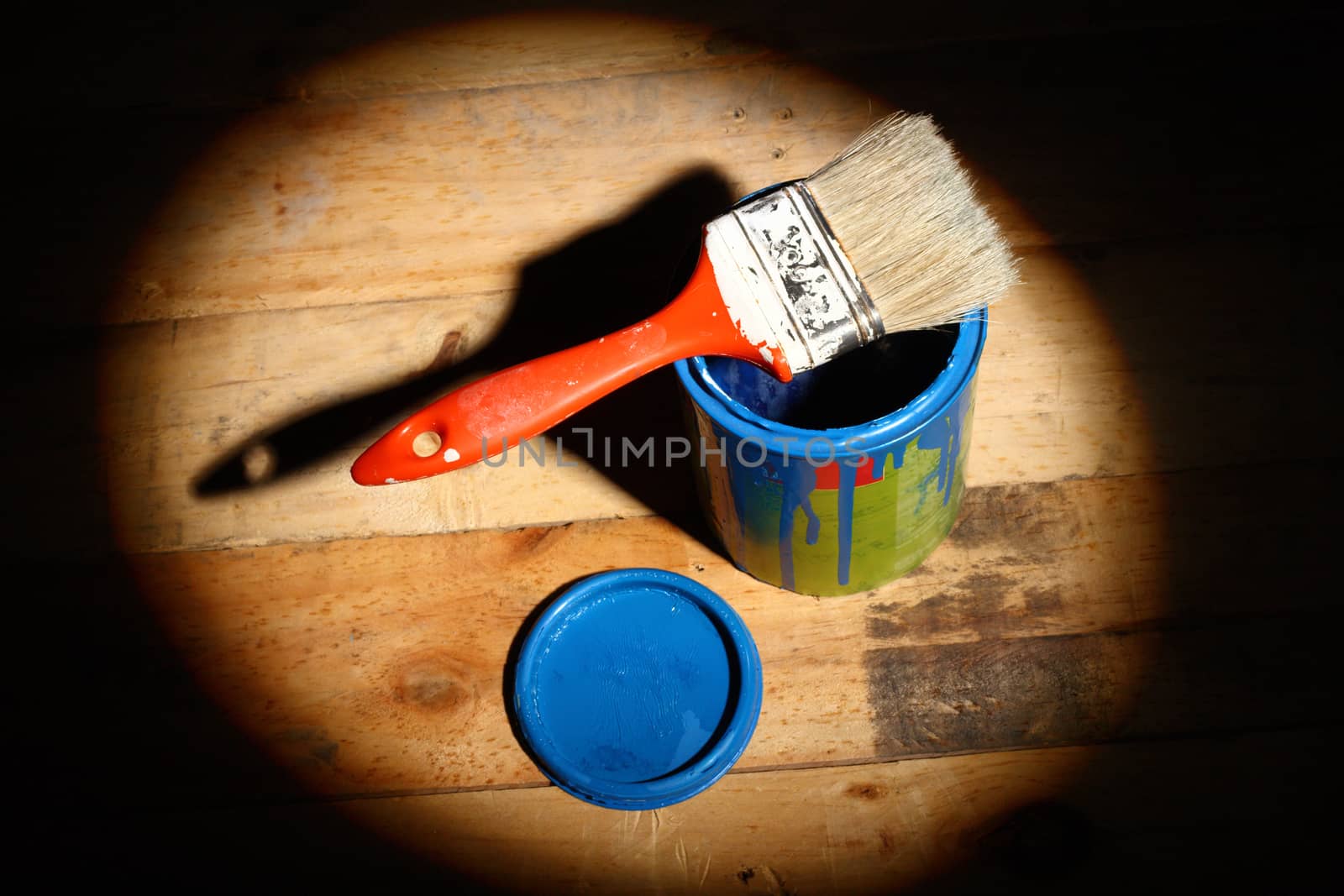 brush painting on tin can of blue paint  in the spotlight