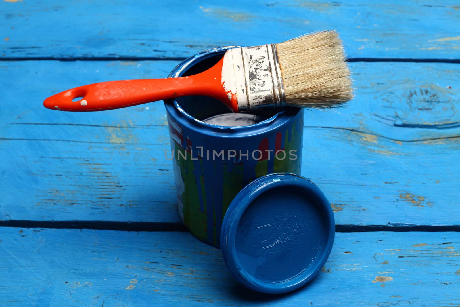 brush painting on tin can of blue paint