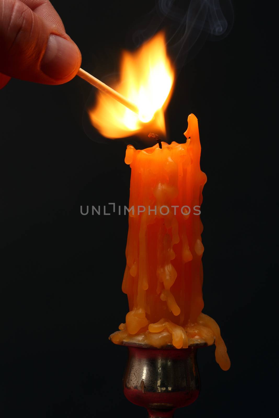 Hand lighting a candle with match stick 