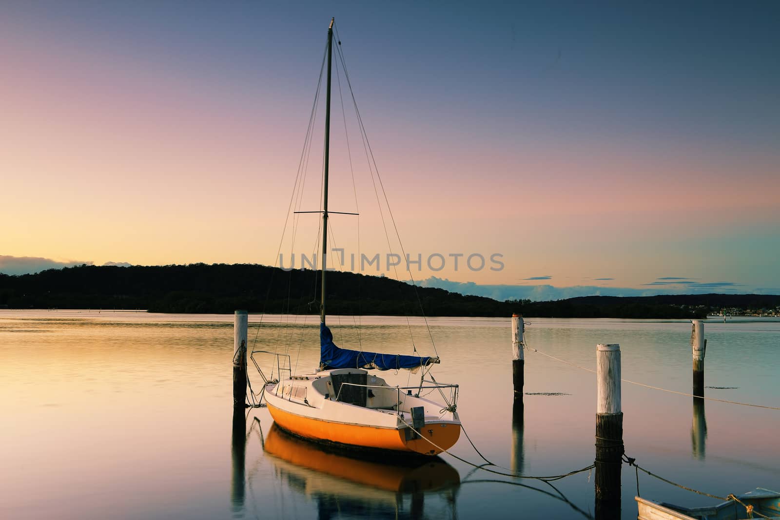 Little sailing boat or yacht tied to its moorings.  Sunrise at Woy Woy, N/SW, Australia.  Woy Woy is aboriginal Wy Wy, which  means "much water" or "big lagoon"
