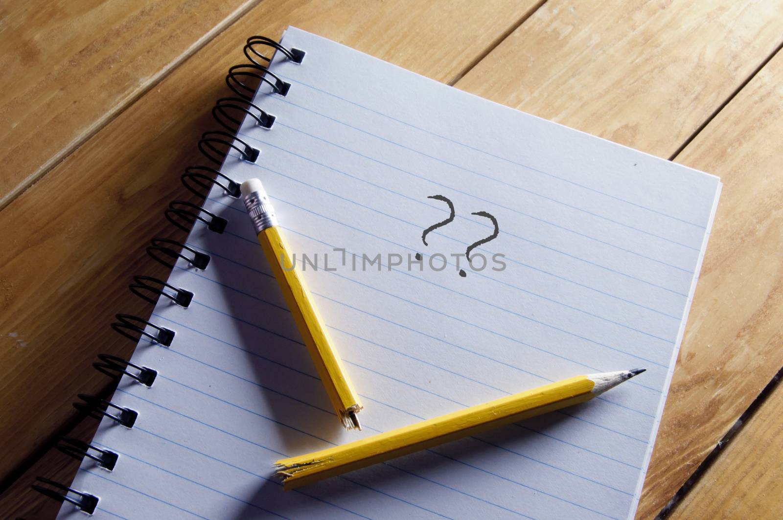 Questions mark and broken pencil on top of a note pad