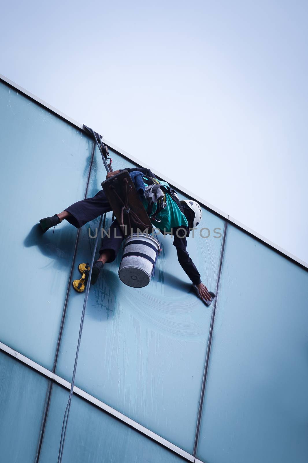 worker cleaning windows service on high rise building