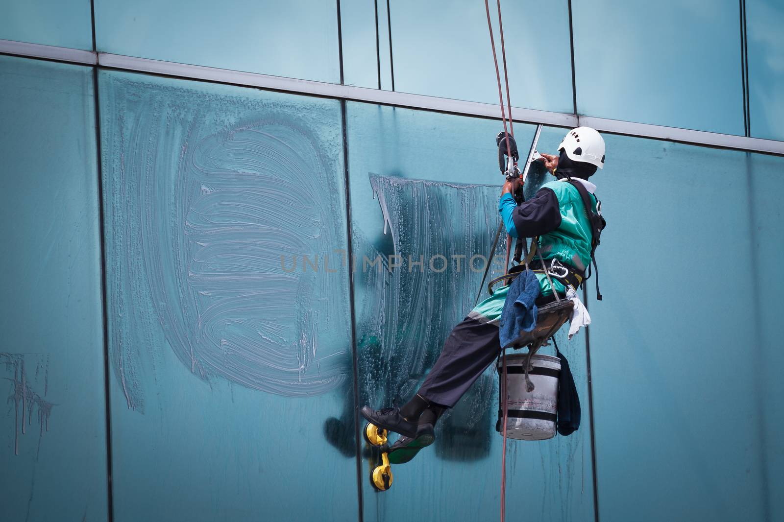 worker cleaning windows service on high rise building