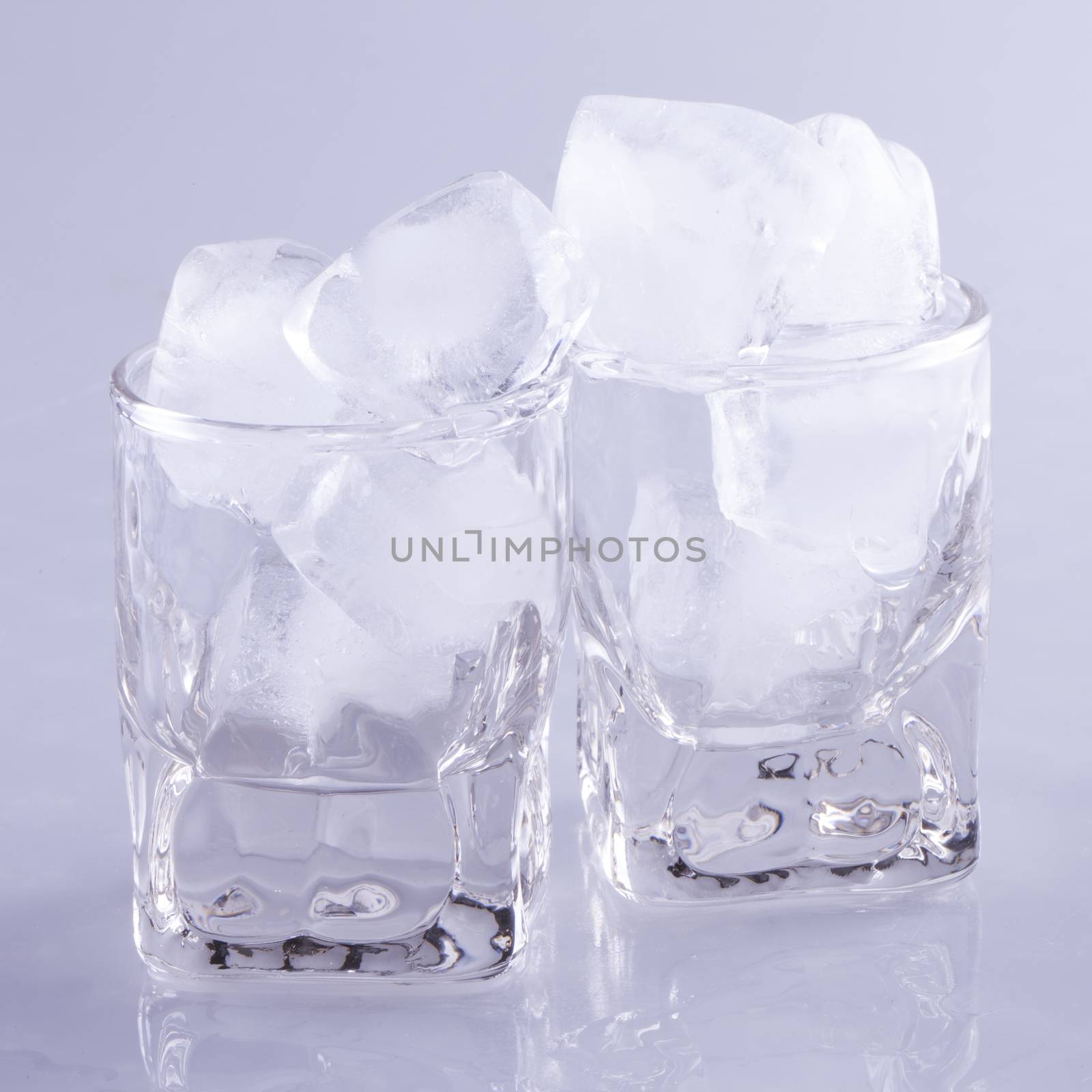 Small glasses full of ice cubes, over gray background