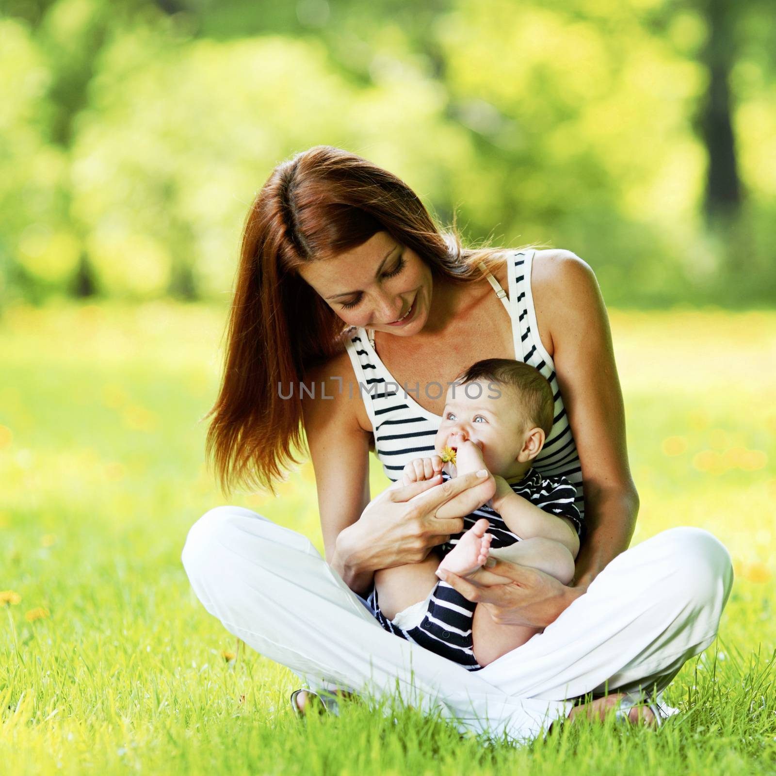 Mother and daughter sitting on grass in spring park