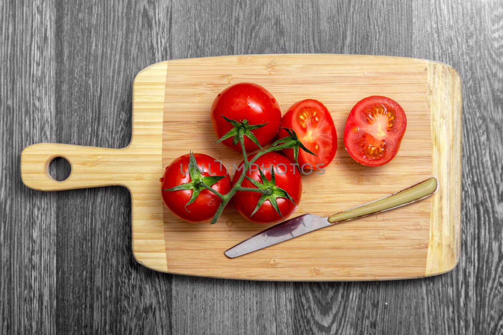 Top view of fresh tomatoes and knife on chopping board  by Elisanth