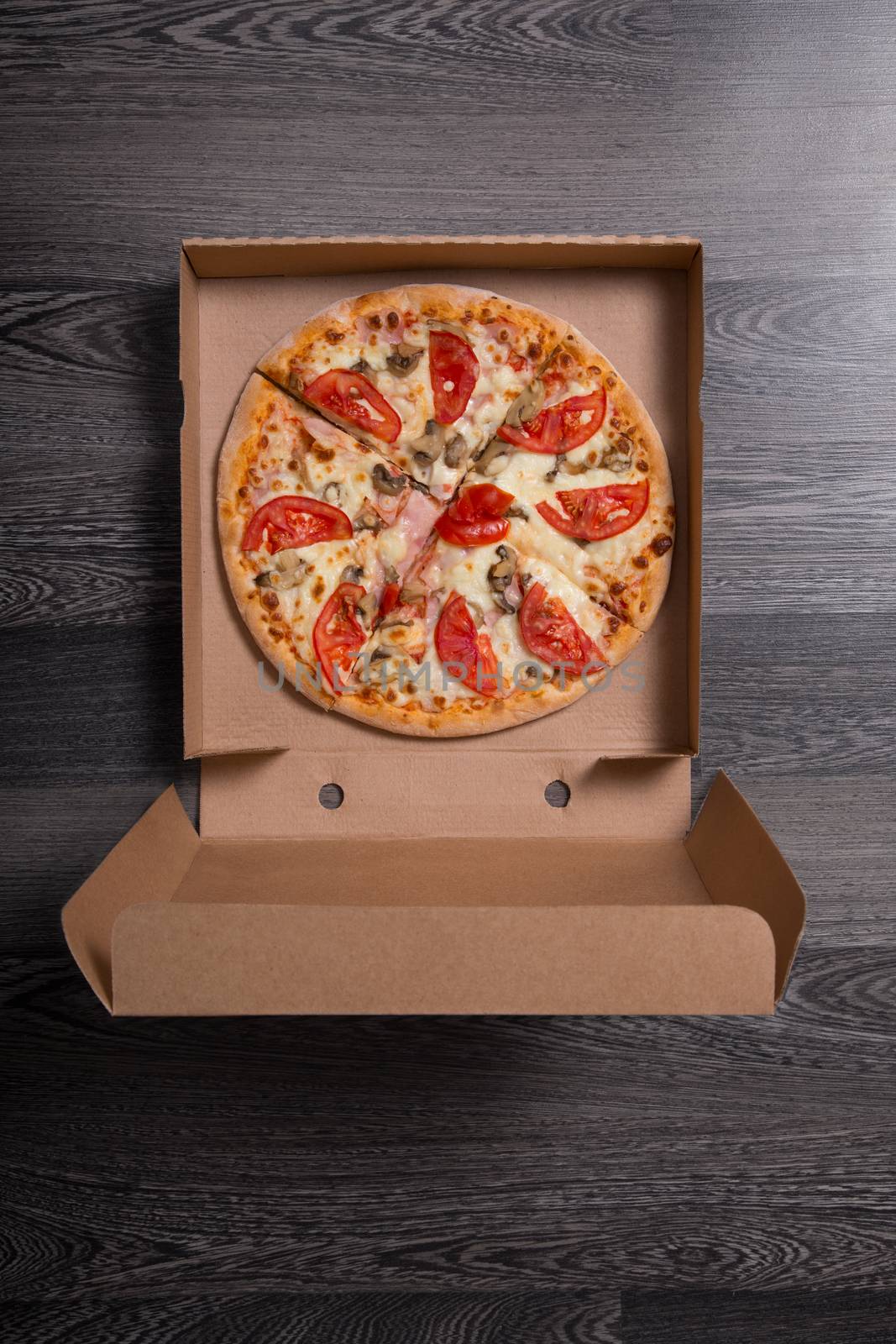 Italian pizza with ham and tomatoes in box, on gray table background 