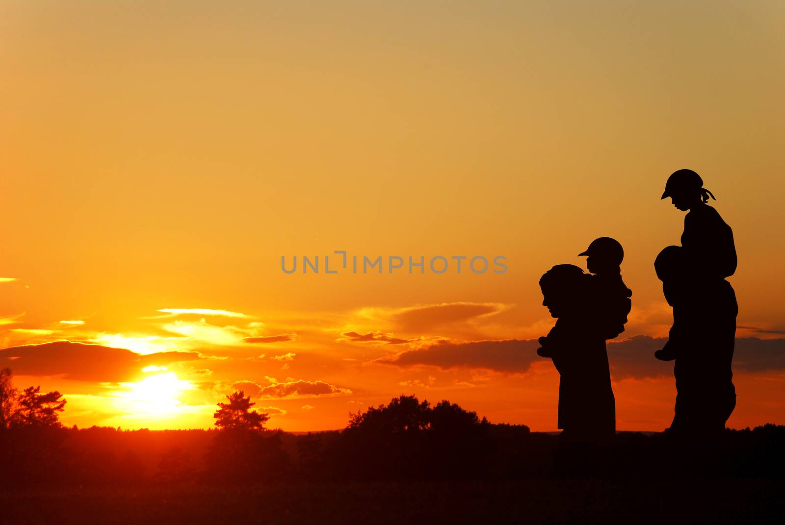 children on the shoulders of parents go summer evening, silhouettes on sunset