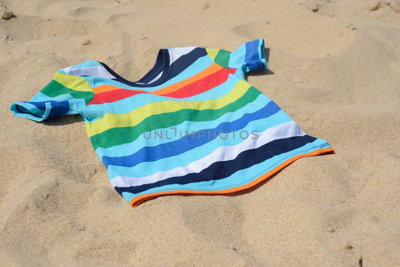 Multicolored child t-shirt on the sand by anytka