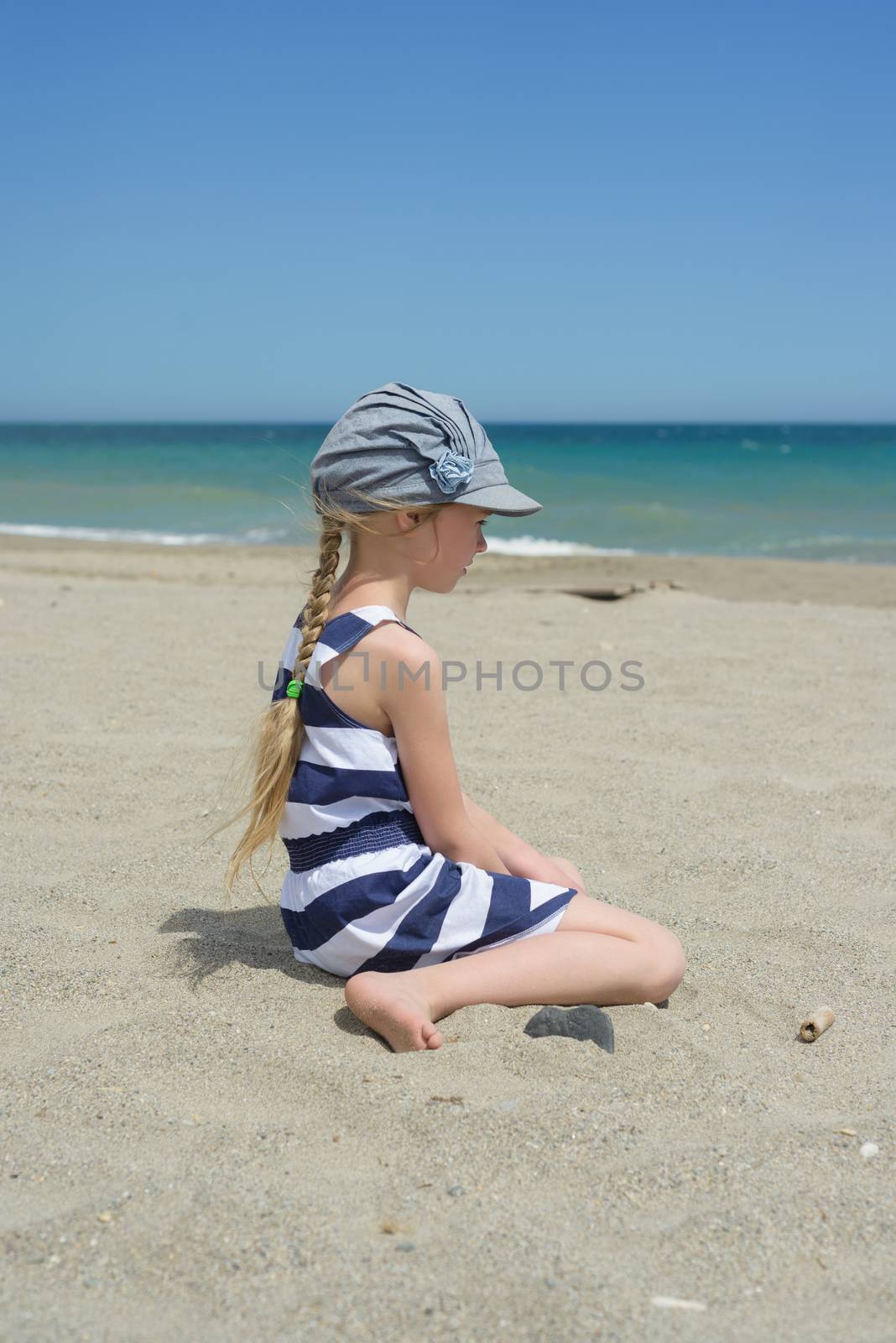 Blonde little girl sitting on the beach
