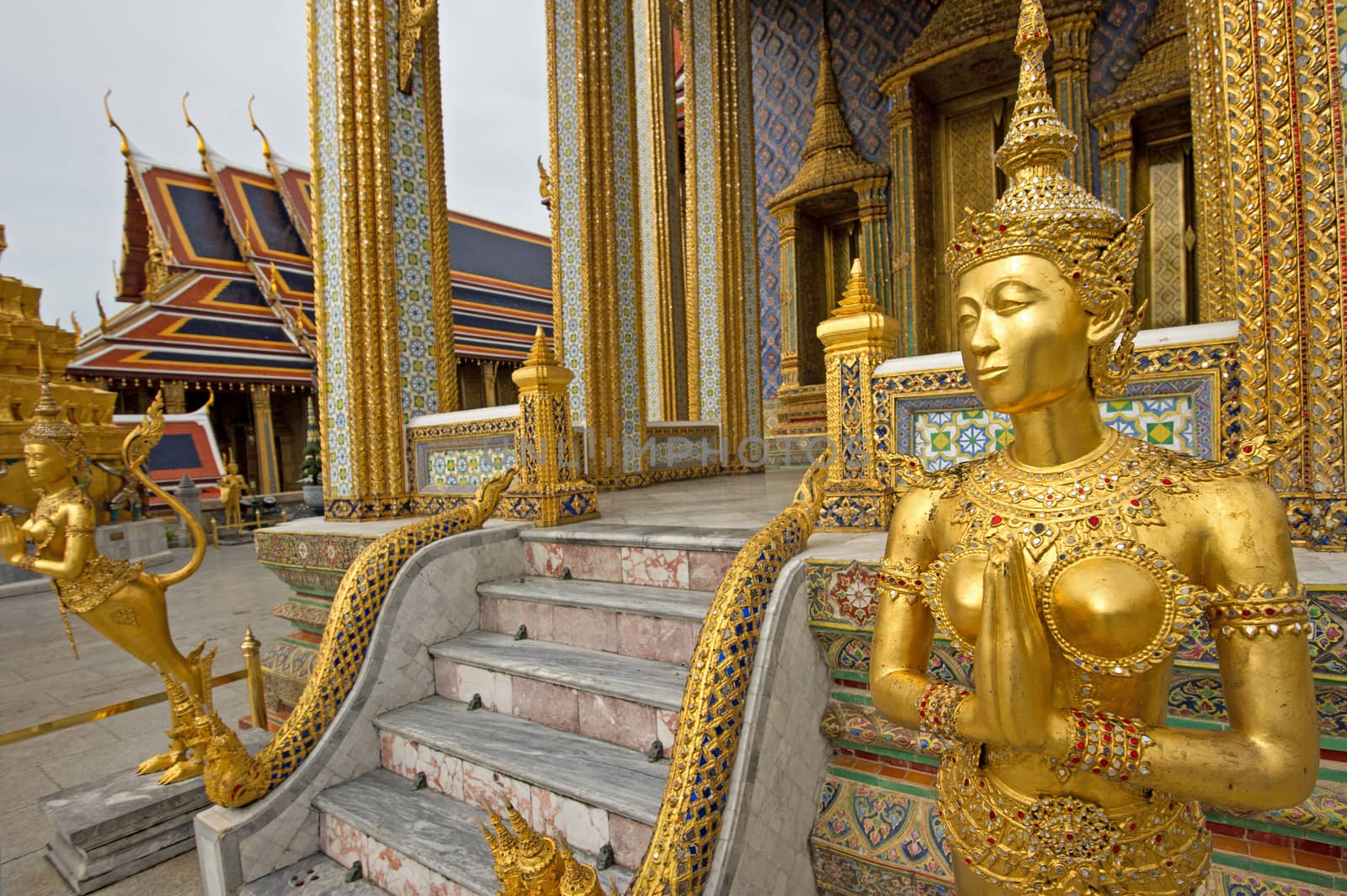 A Golden Kinnari statue in Wat Phra Kaew, Bangkok, Thailand by think4photop