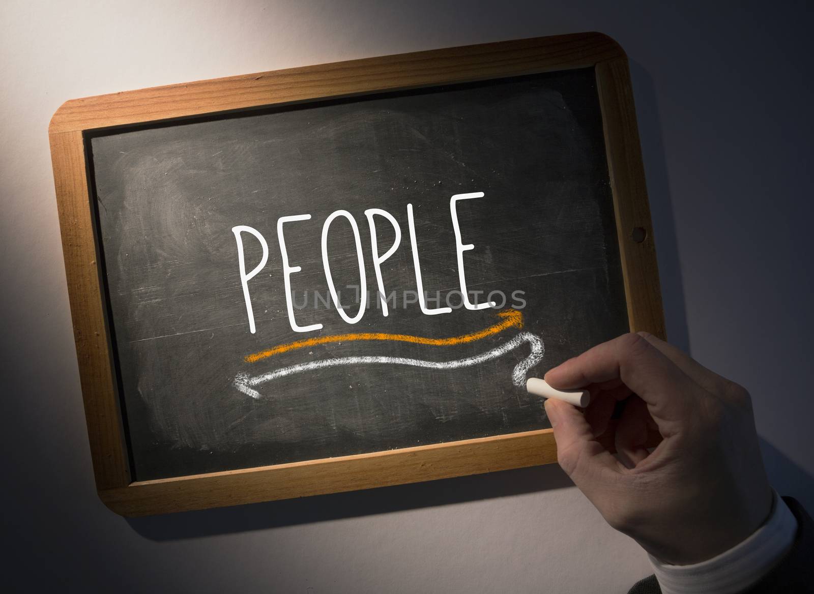 Hand writing the word people on black chalkboard