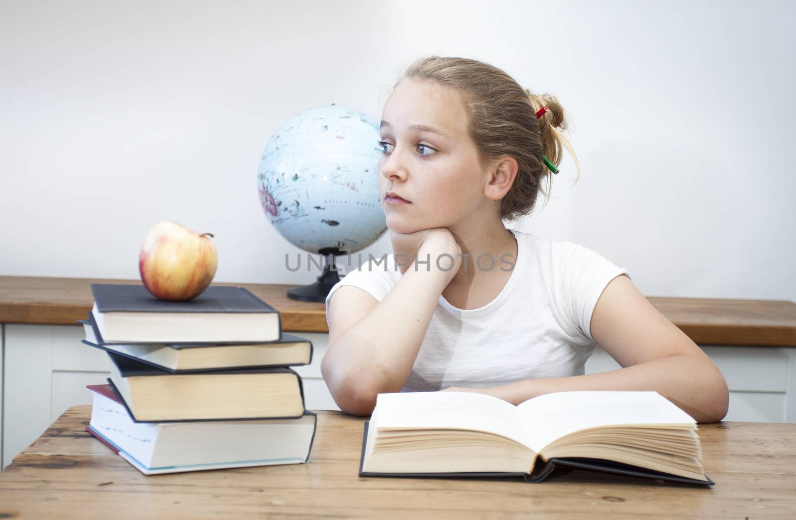 A high school student daydreaming doing her homework