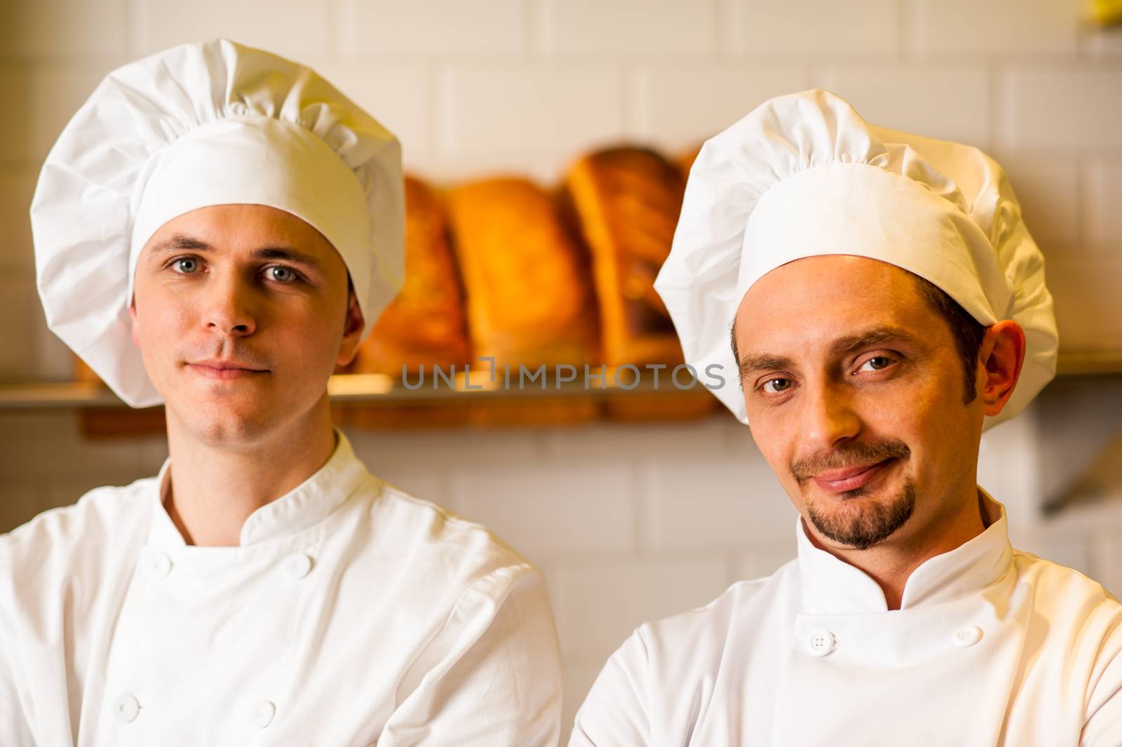 Young smiling chefs posing in bakery by stockyimages