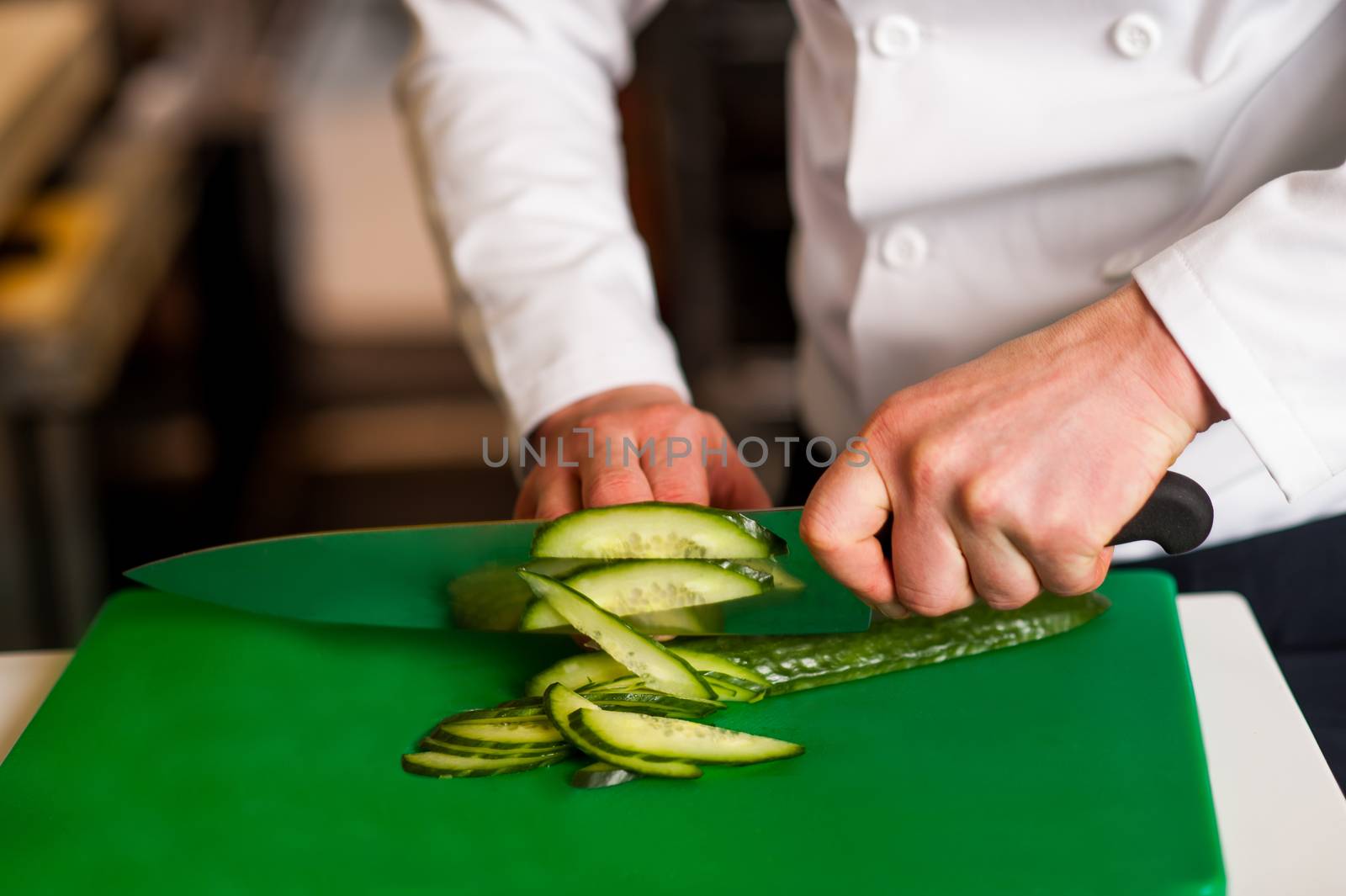 Chef chopping leek over green carving board by stockyimages