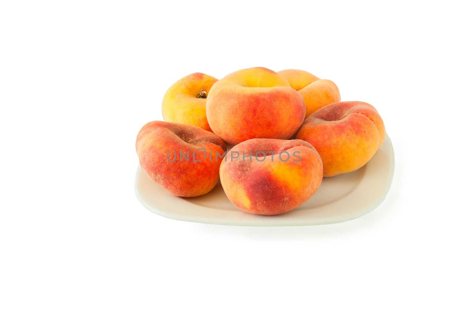New variety of flat peaches lies on a white plate against a white background
