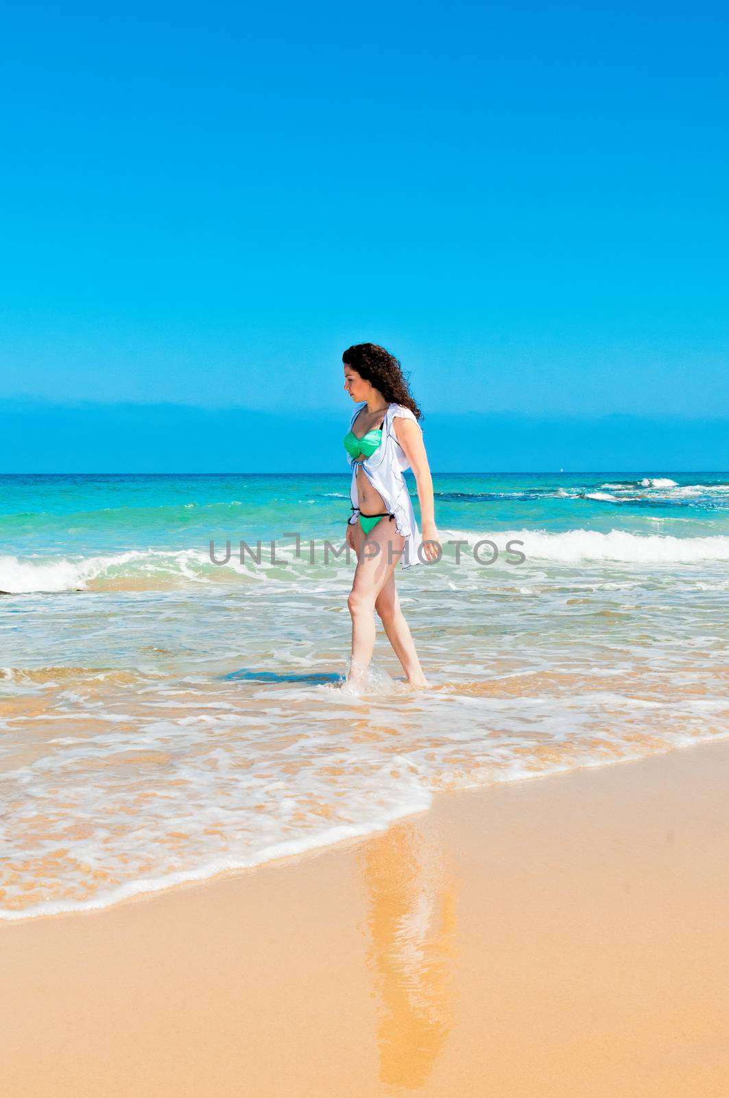Girl in green bathing suit and white cloak walking on water from the rolling waves