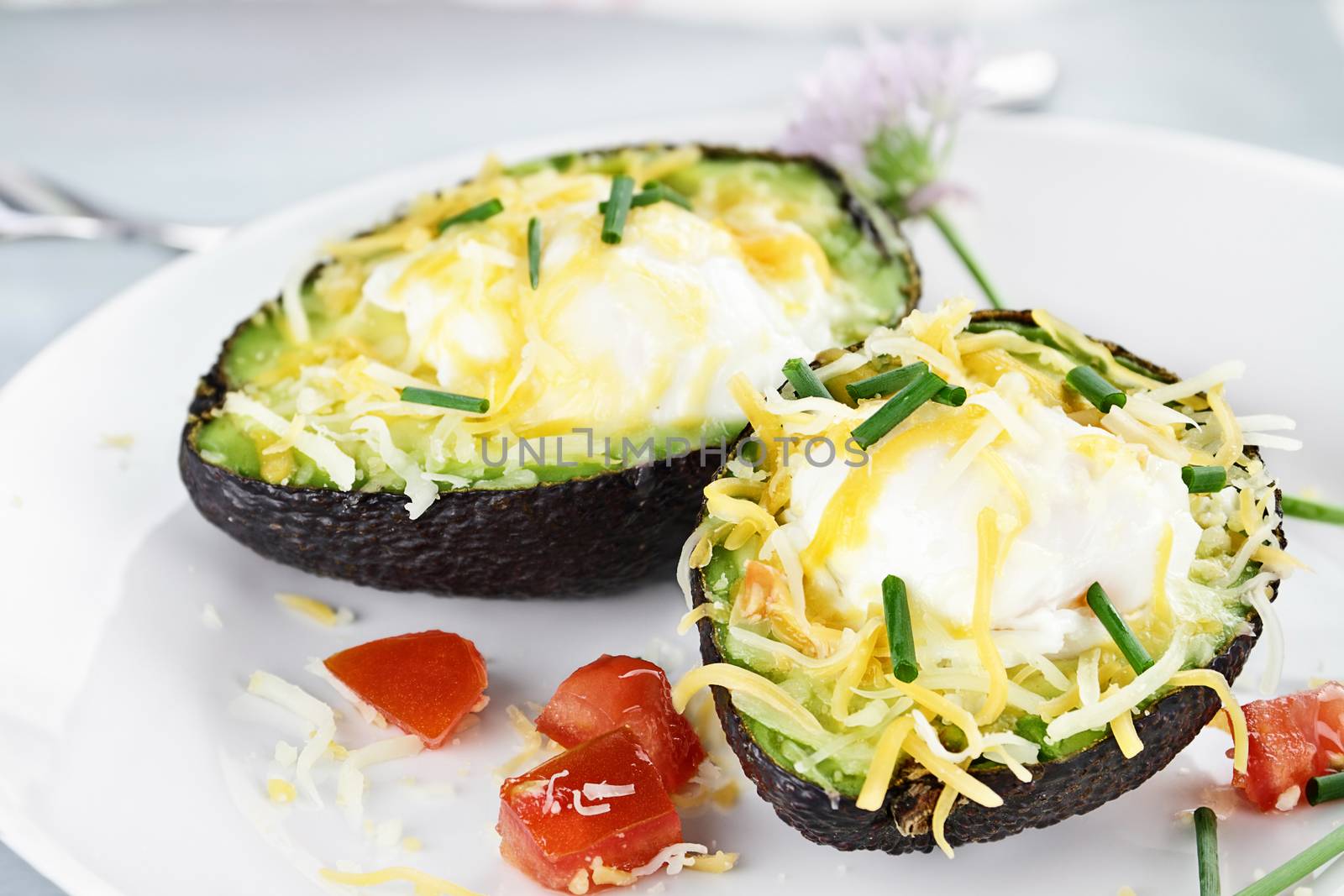 Eggs with cheddar cheese baked in fresh avocados and garnished with chives. Extreme shallow depth of field.