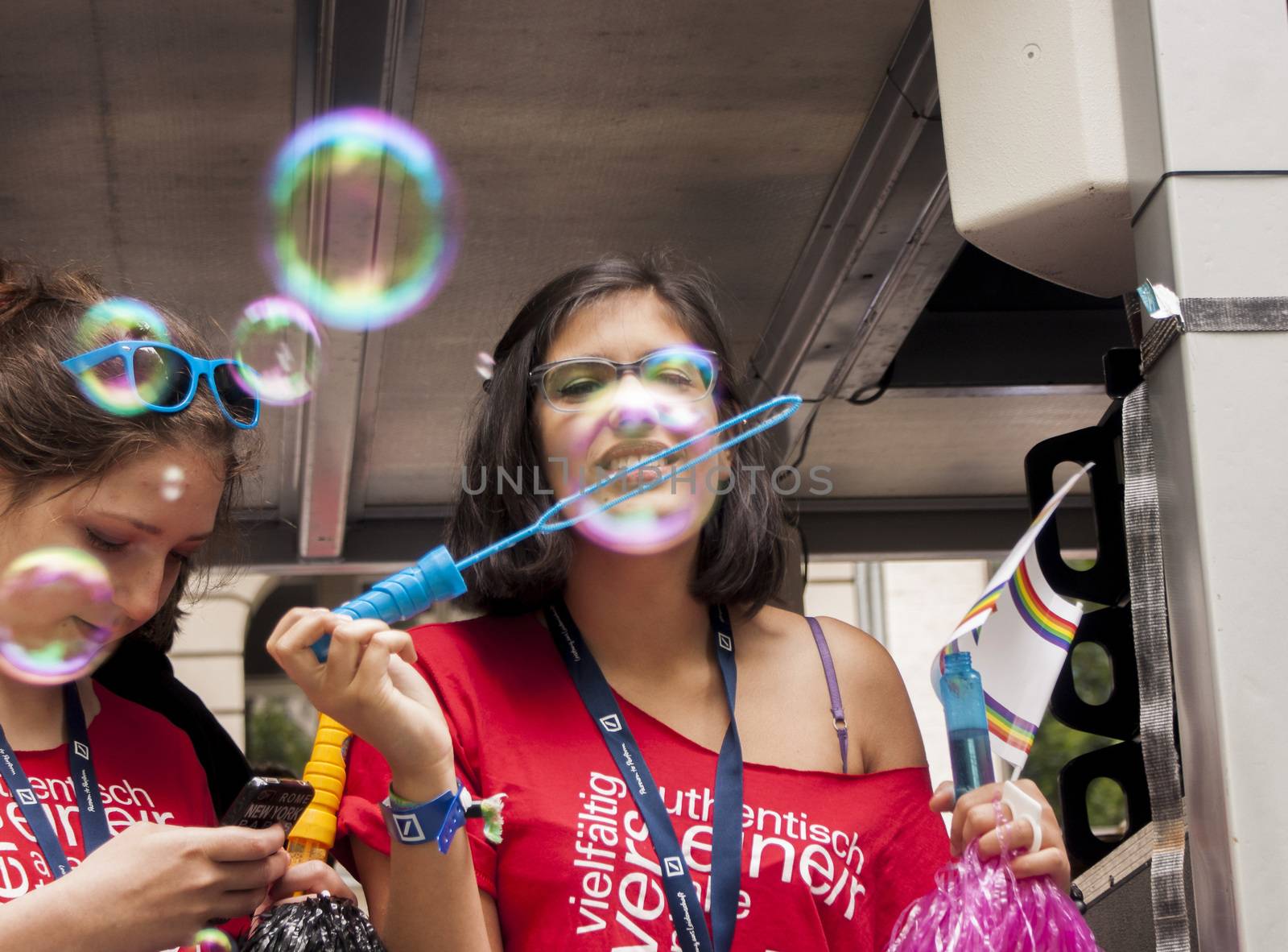 BERLIN, GERMANY - JUNE 21, 2014: Christopher Street Day.Crowd of people Participate in the parade celebrates gays, lesbians, bisexuals and transgenders.Prominent in the image a attractive girl making soap bubbles. 