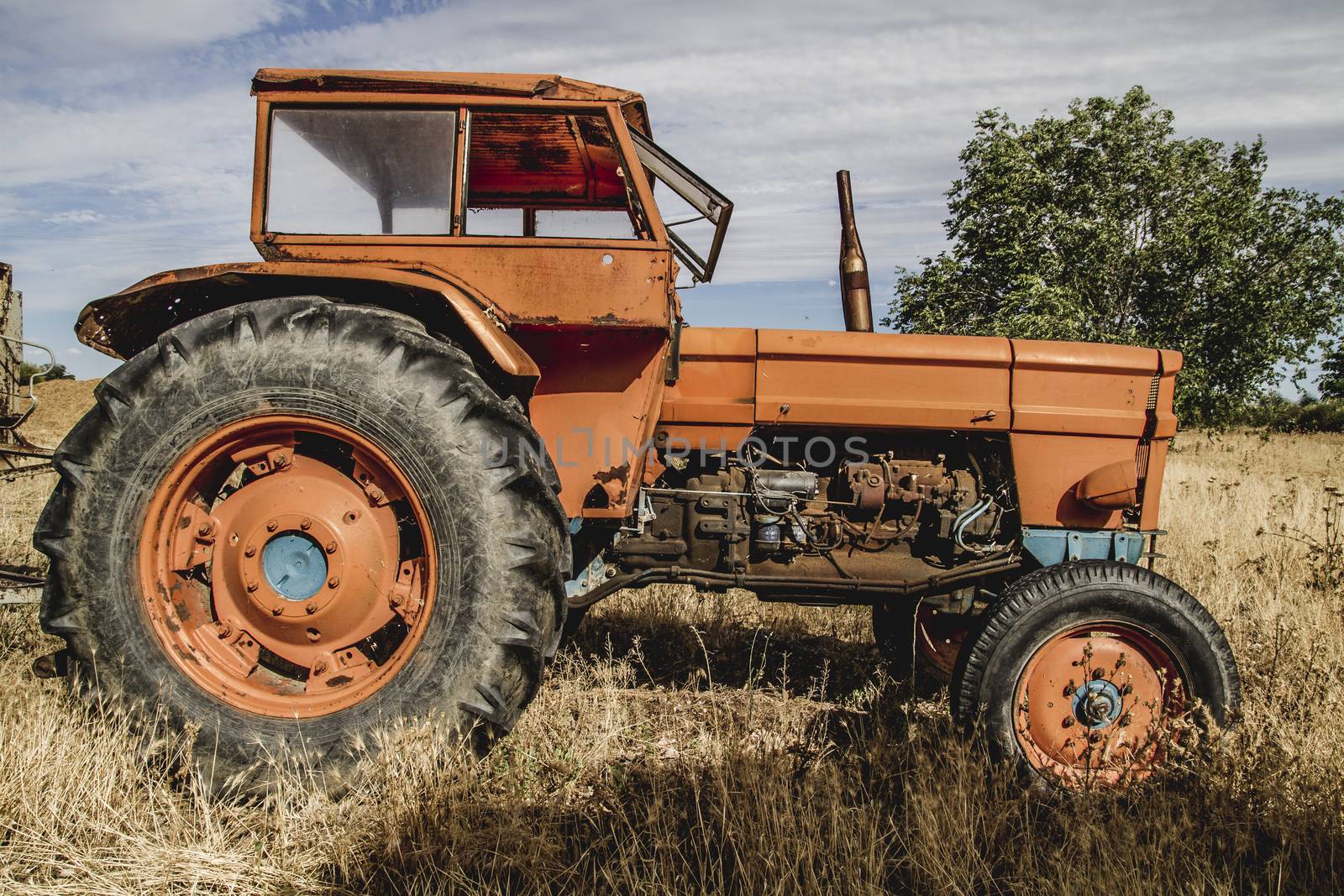 old agricultural tractor abandoned in a farm field by FernandoCortes