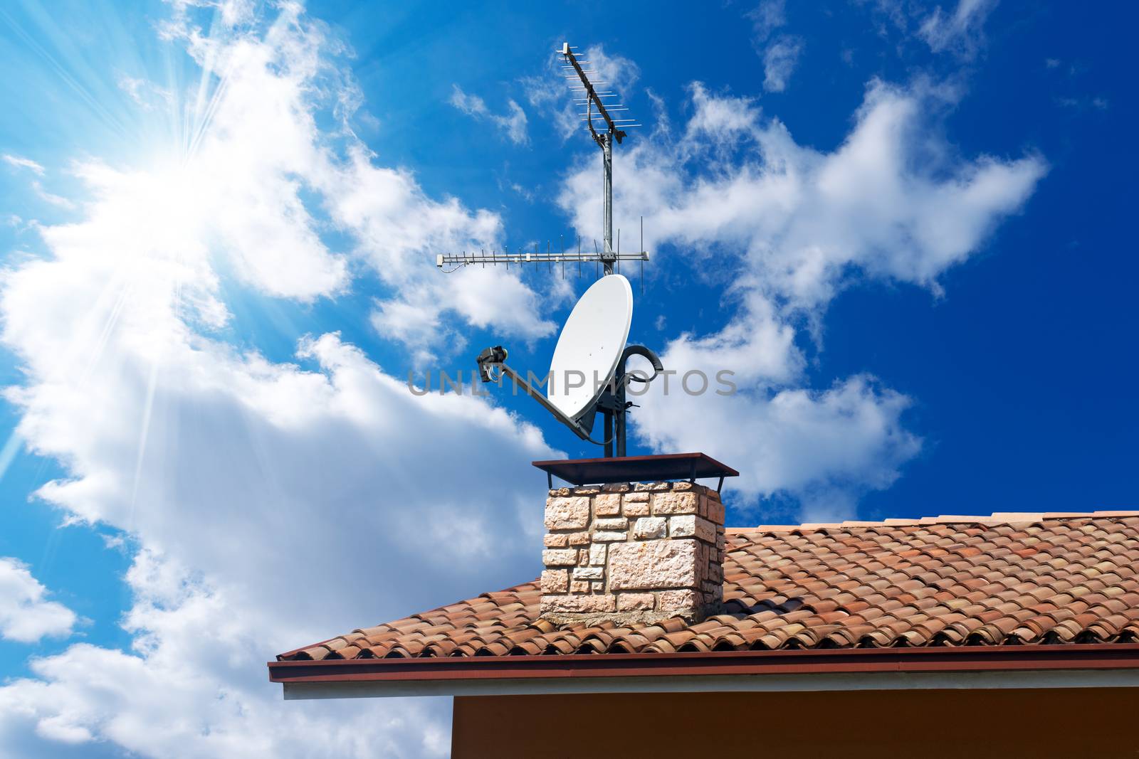 Satellite dish and TV antennas on the house roof with a beautiful blue sky