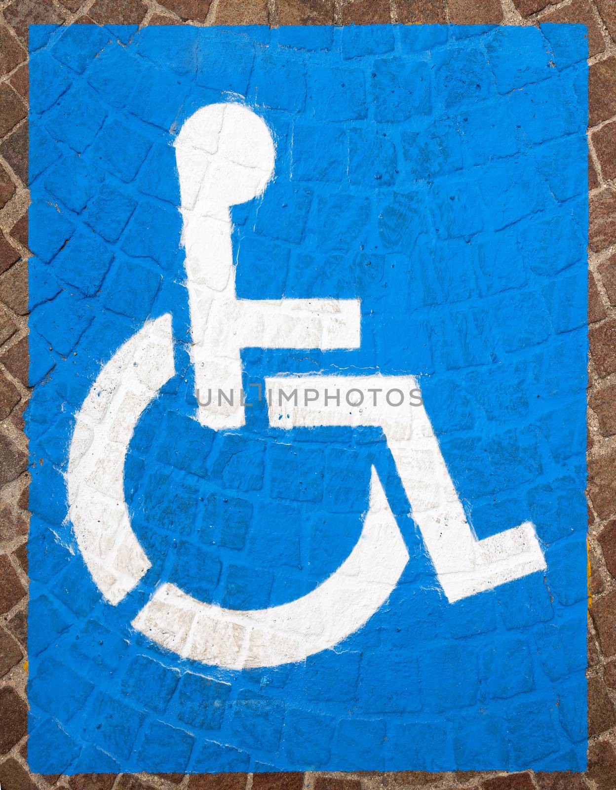 Blue and white road marking for disabled parking on floor with blocks of porphyry