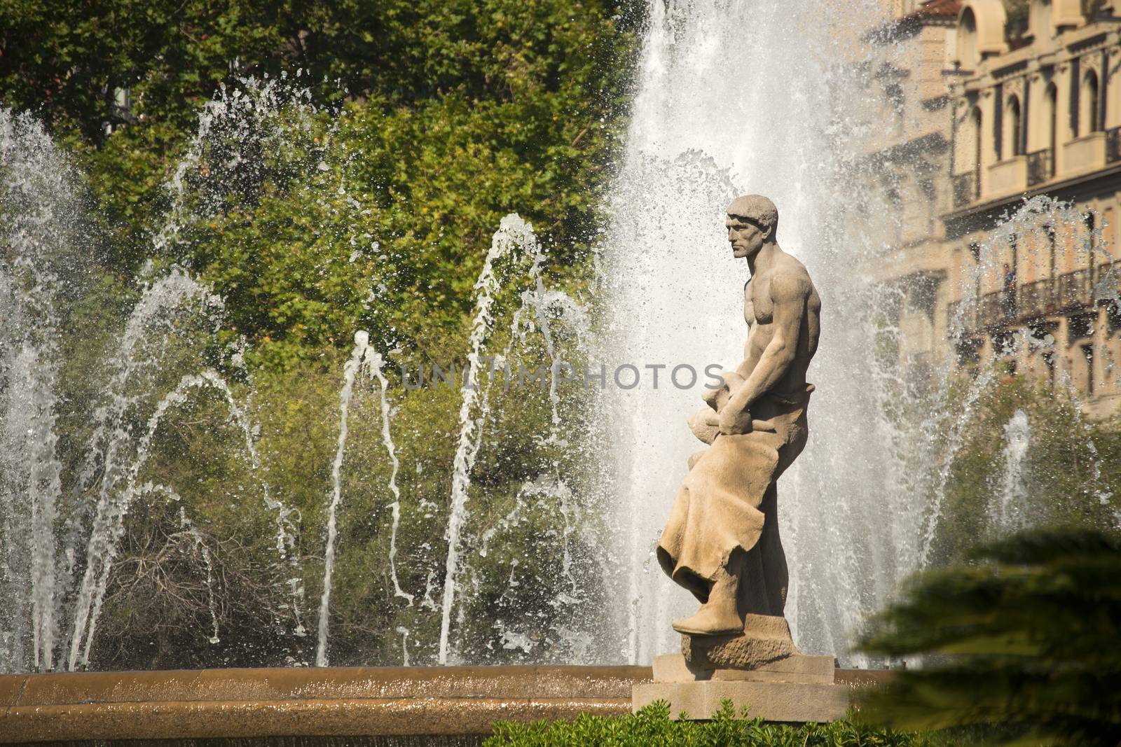 Fountain and stone statue in the central Catalunya square (Placa Catalunya) in Barcelona, Spain