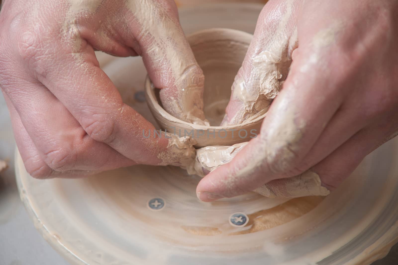 Hands of a potter, creating an earthen jar on the circle