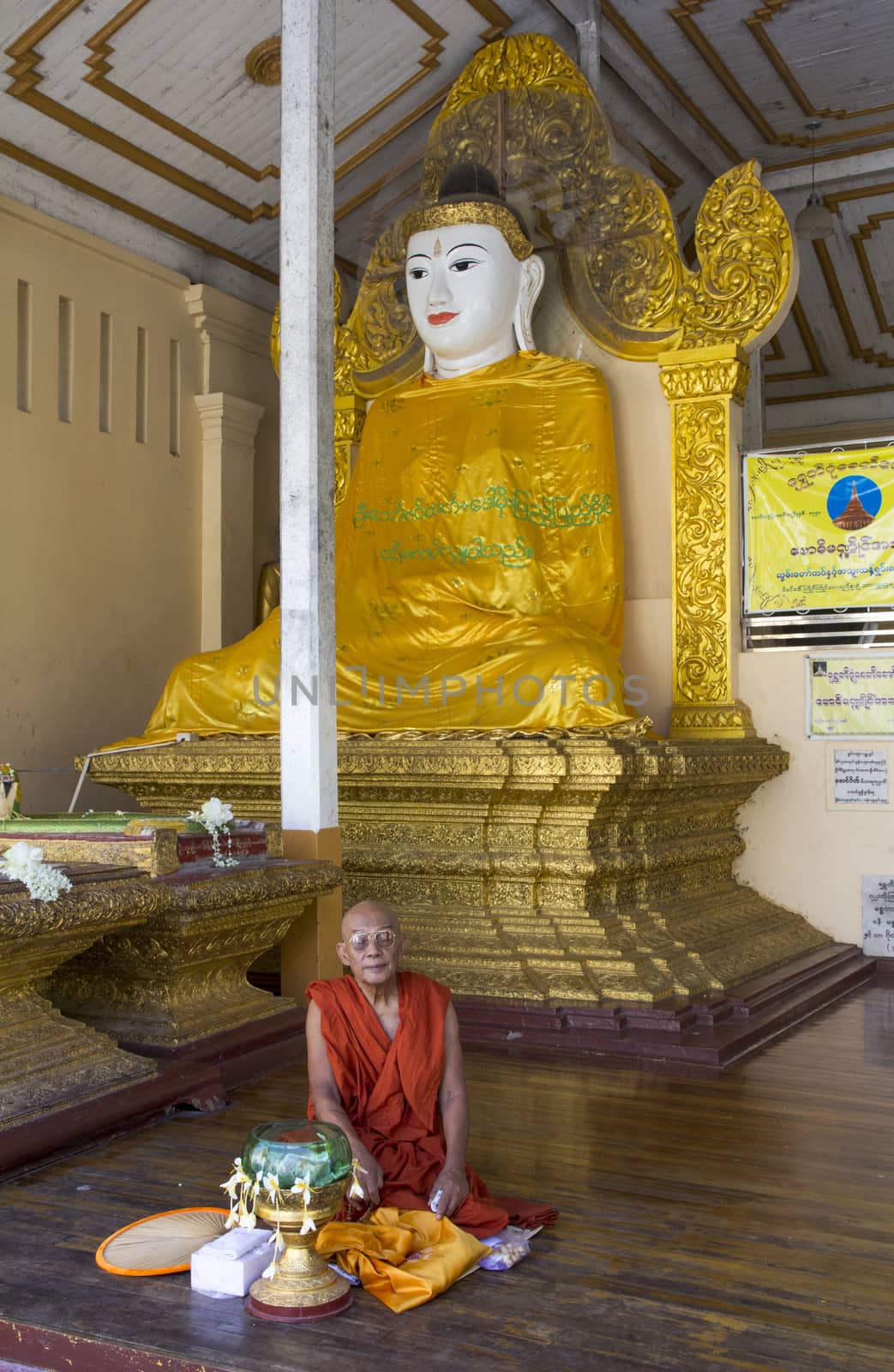 Yangon, Myanmar-May 6th 2014: A monk meditates beside a buddha statue in Shwedagon Pagoda. Some structures are reputed to be 2,500 years old