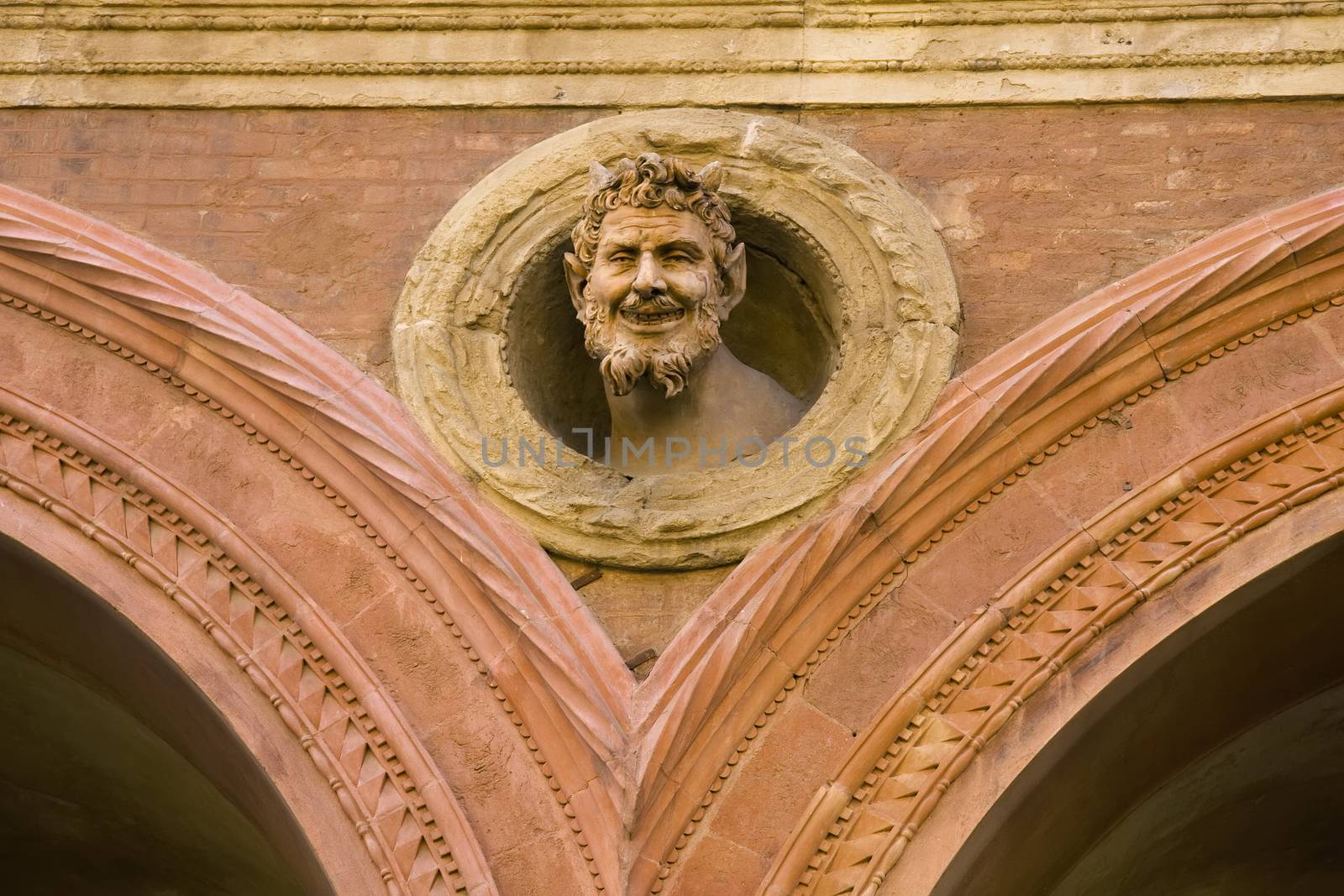 The devil's head decoration on medieval building in Bologna by fotoecho