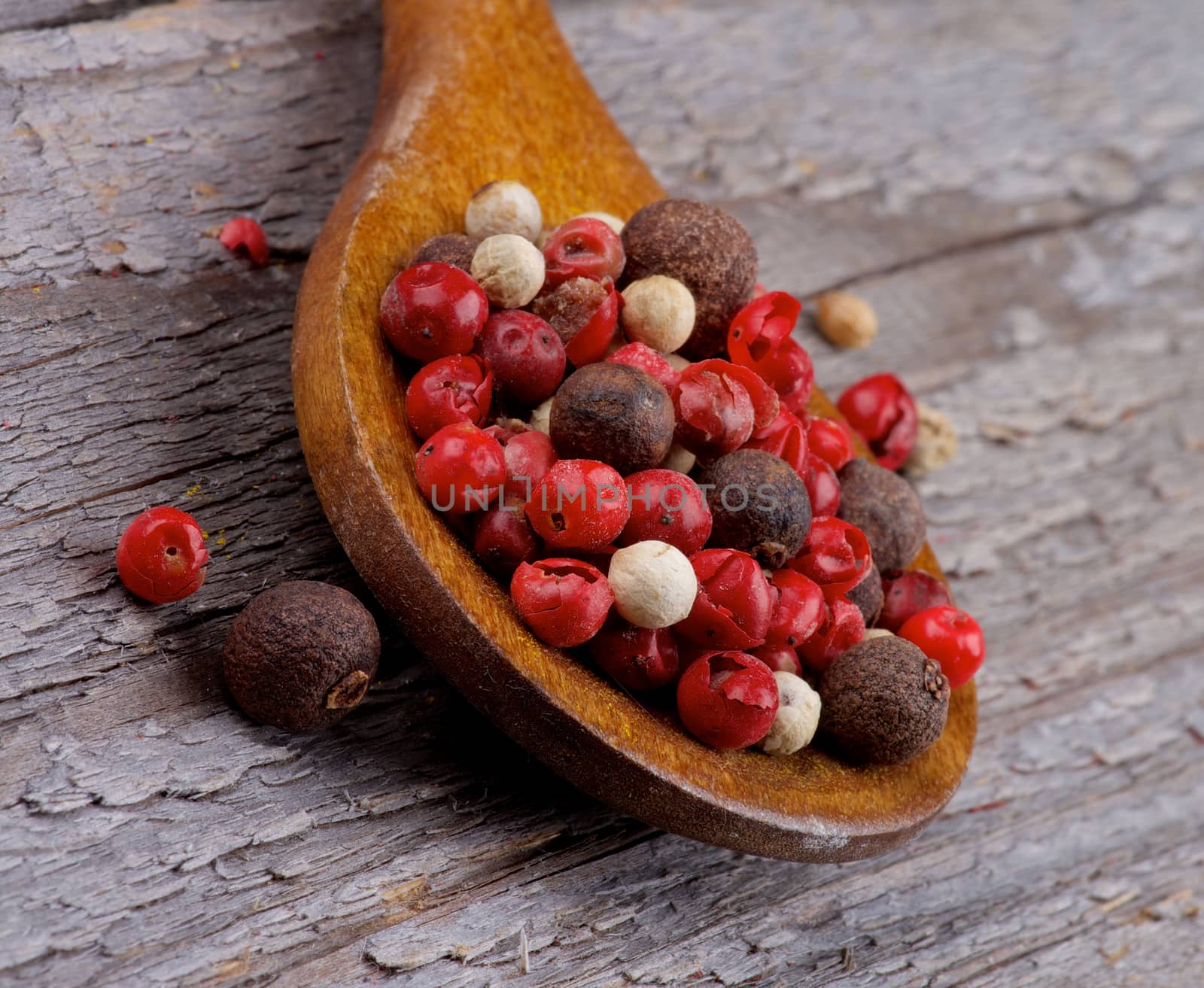 Mixed Red, Black and White Peppercorn in Wooden Spoon closeup on Rustic Wooden background