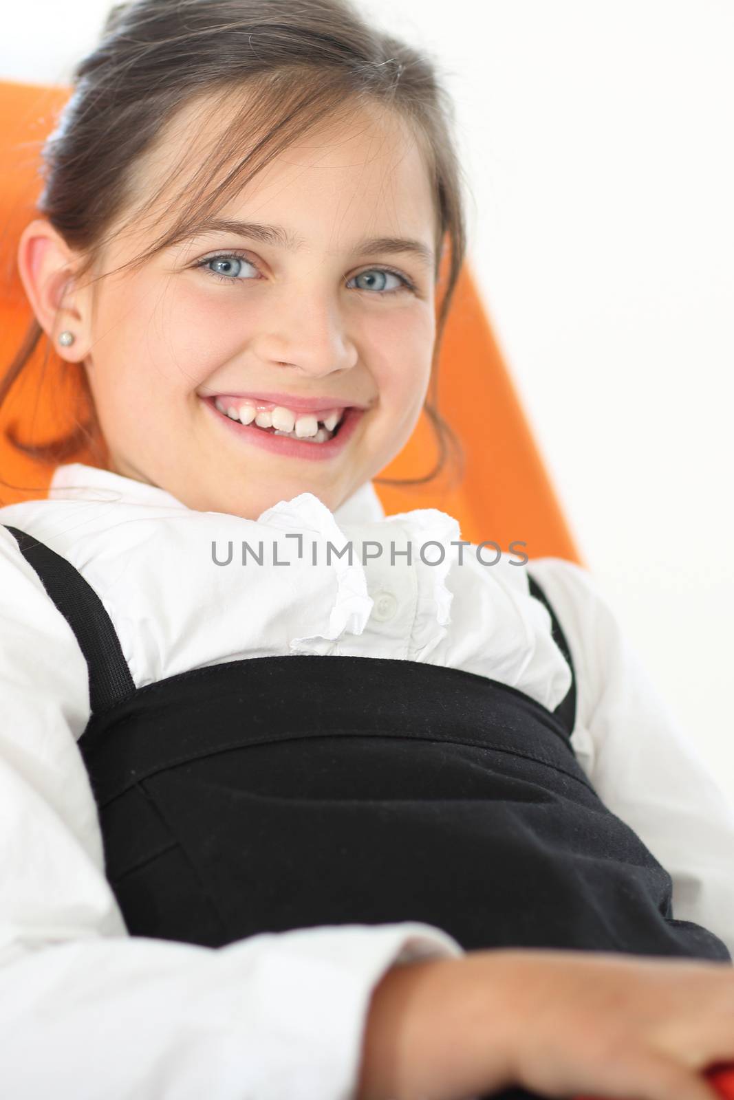 Joyful girl reading a book sitting on the orange chair