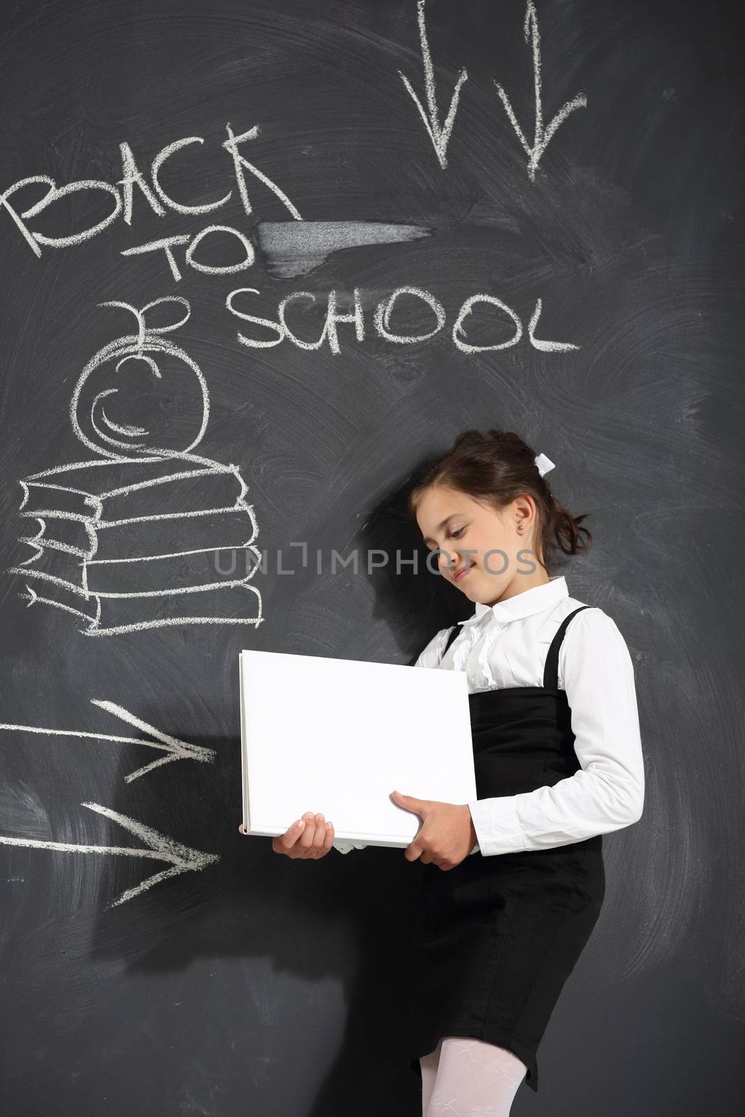 Cute little girl standing by a black school board