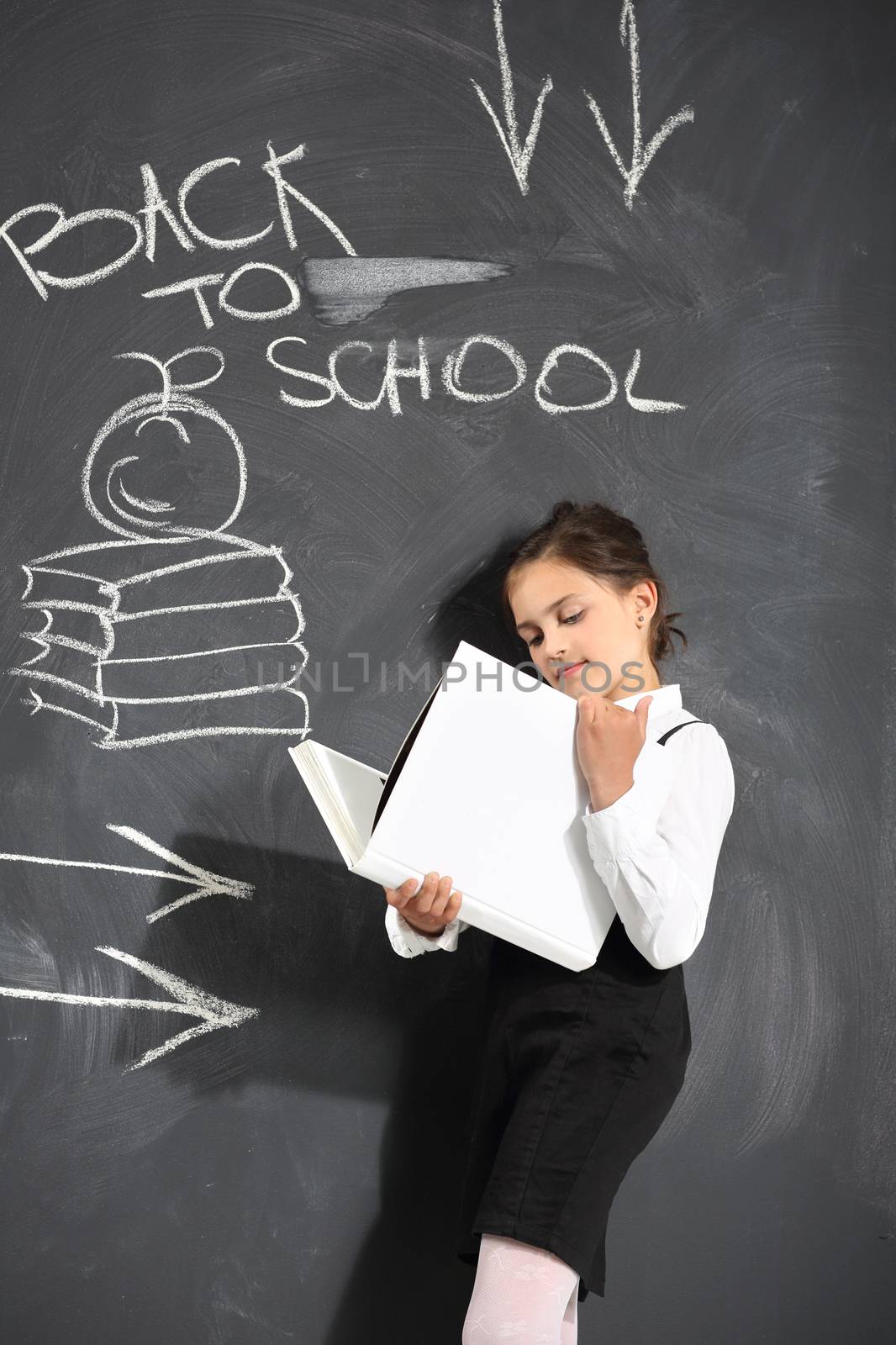 Cute little girl standing by a black school board