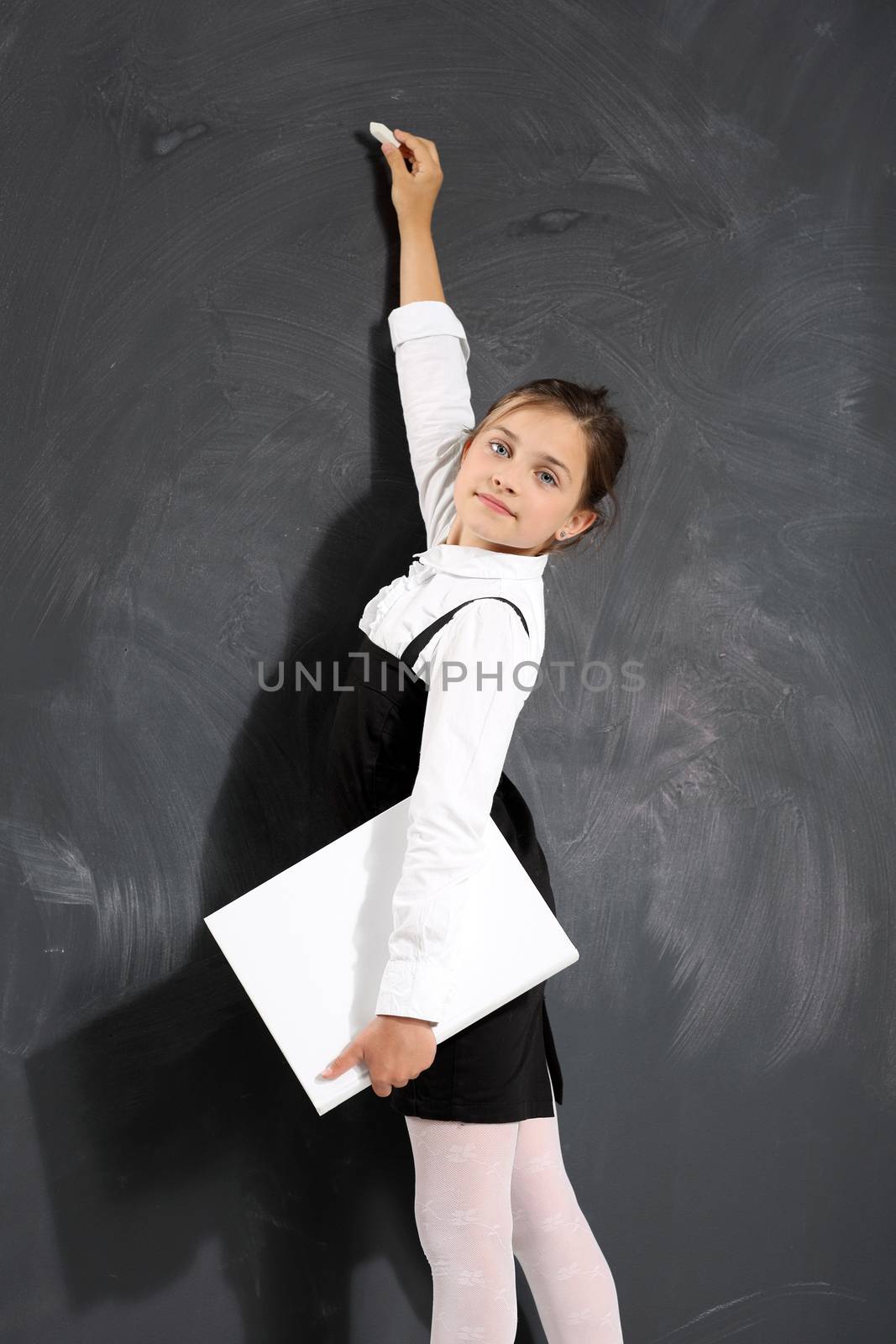 Girl in school uniform on a white background with a textbook in hand