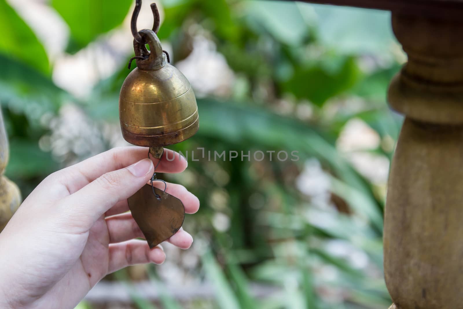 Hand ringing small Thai style bell, typically in temple