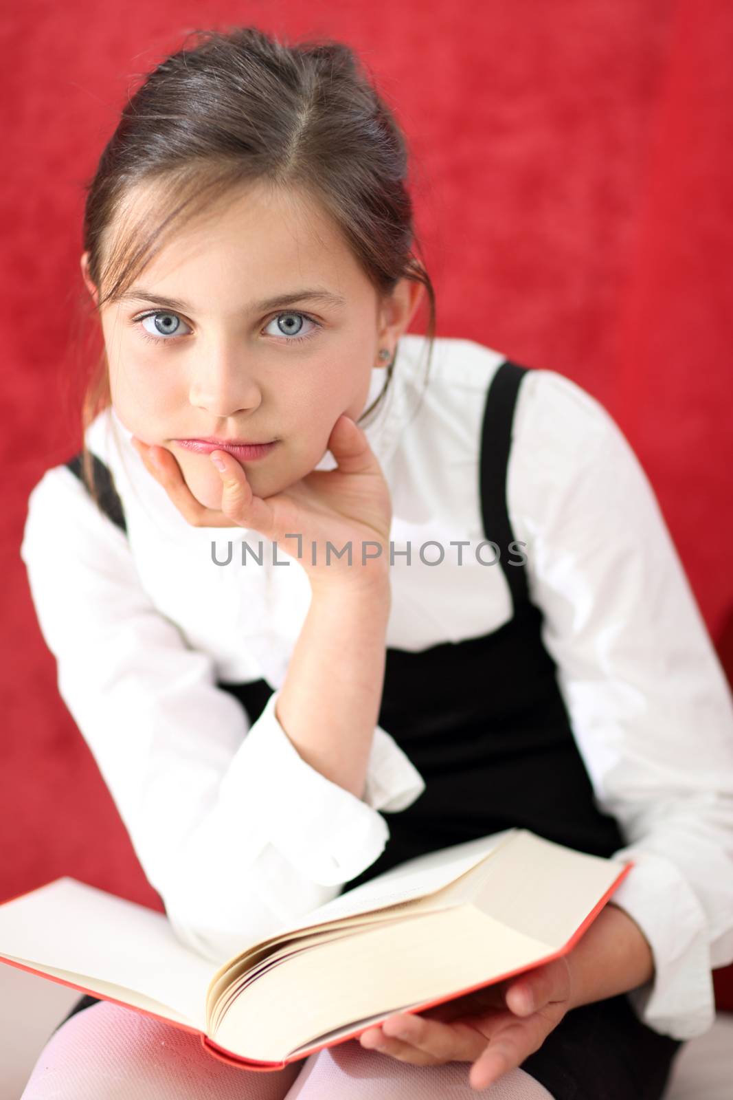 Joyful girl reading a book sitting on the orange chair