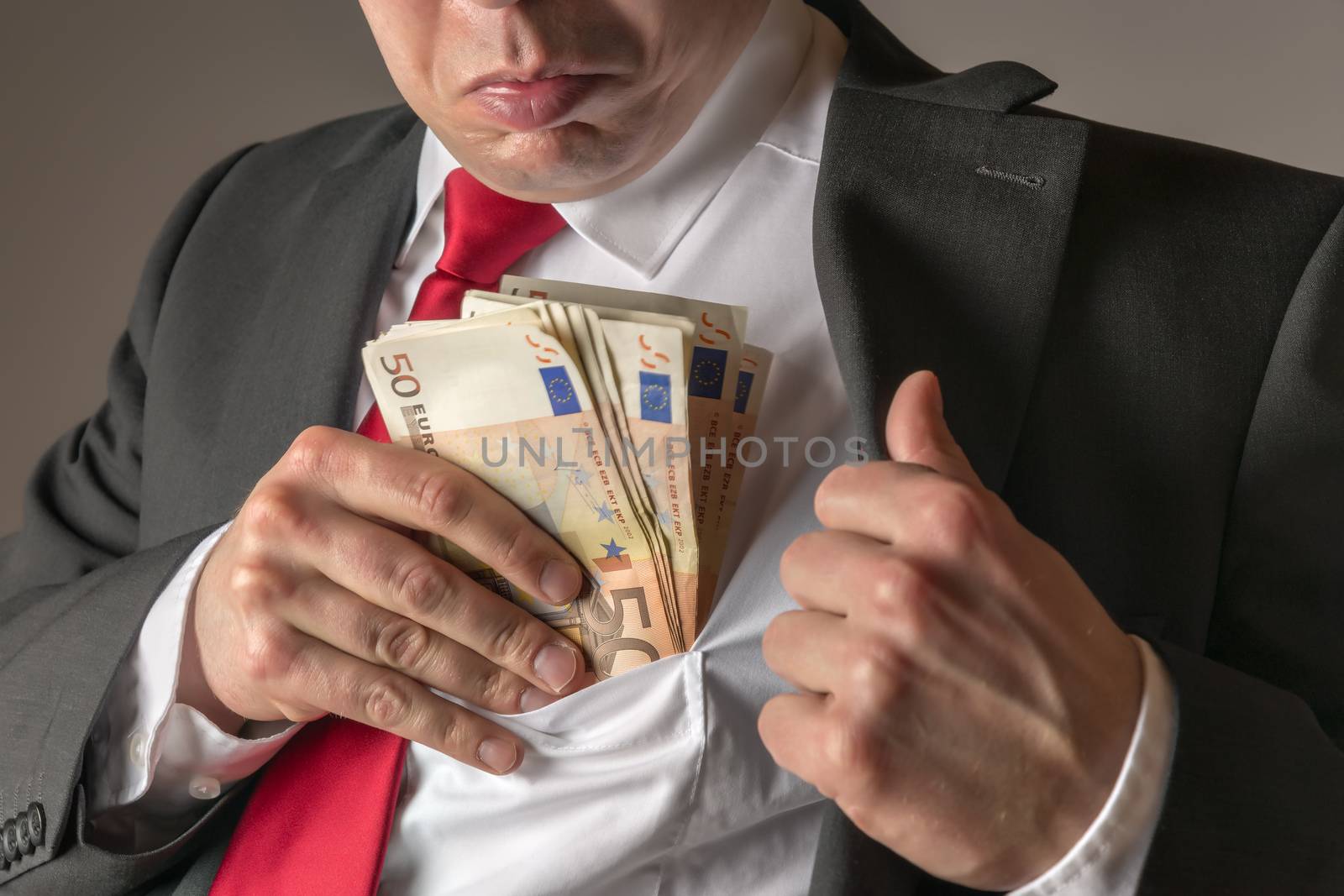 Businessman in dark suit and with tie putting money in his pocket